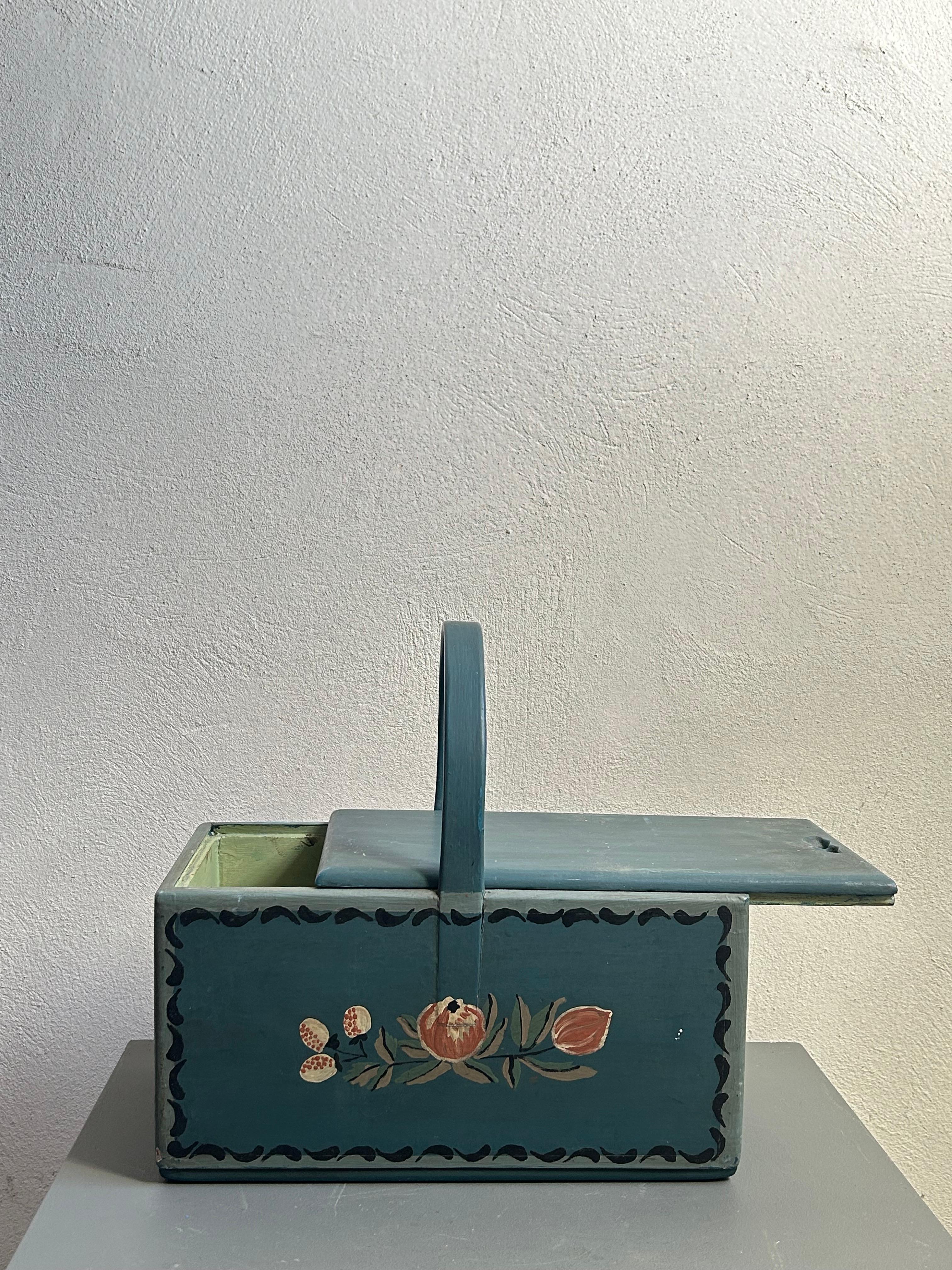 Questo cestino da pranzo in legno allmoge svedese dei primi del Novecento, risalente al 1910 circa, è un ottimo esempio di artigianato tradizionale scandinavo. Dipinto in un classico tono di blu con motivi decorati a mano, presenta dettagli floreali