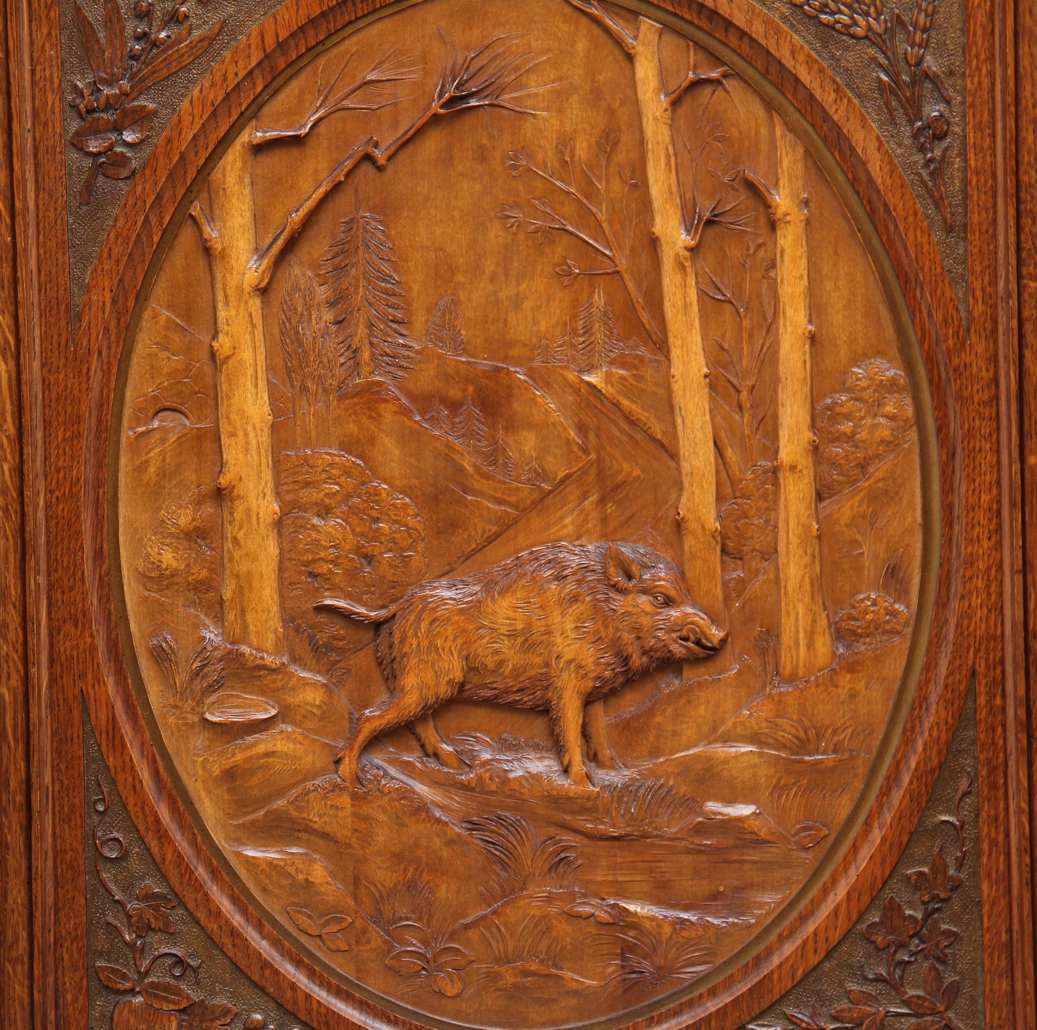 Early 20th century Swiss carved oak panel of a wild boar in a wooded mountainous landscape in a carved oak frame. Signed on the back A.D. Sludt 1902.
 