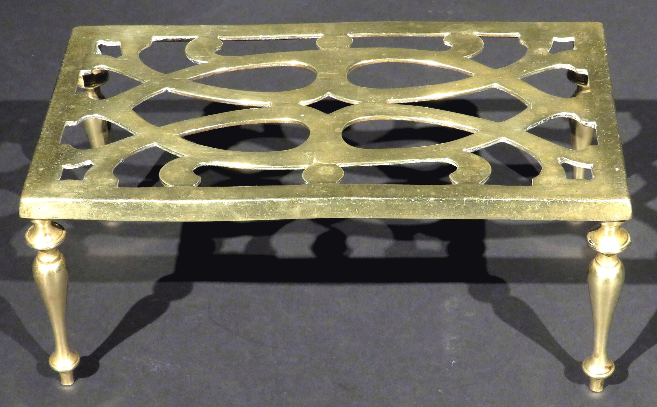 Le plateau rectangulaire percé repose sur quatre supports tournés en forme de balustre, le dessous présentant des marques d'enregistrement britanniques imprimées.
  