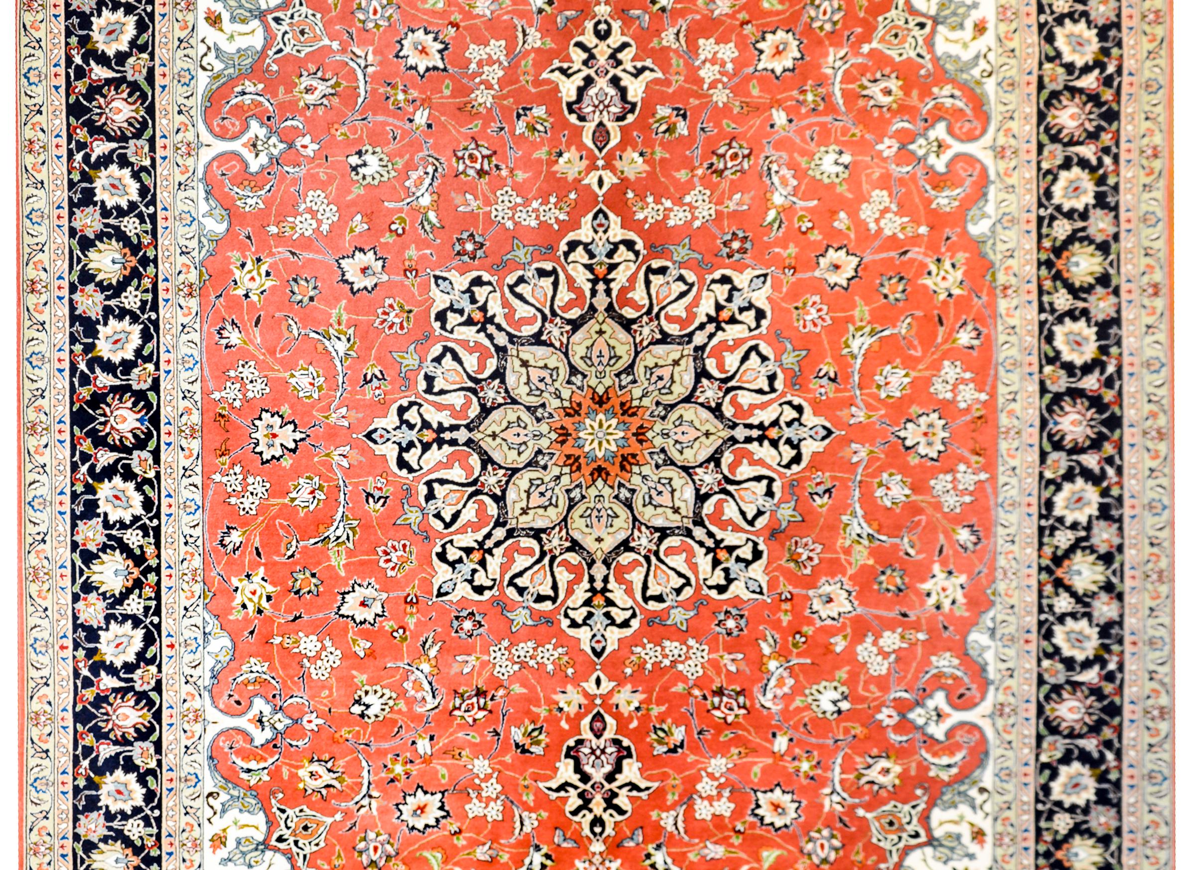 A Persian Tabriz rug with a wonderful large central floral medallion amidst a field of finely woven scrolling vines on an orange background, circa 1980s. The border is complex with multiple petite and large scale floral patterned borders.