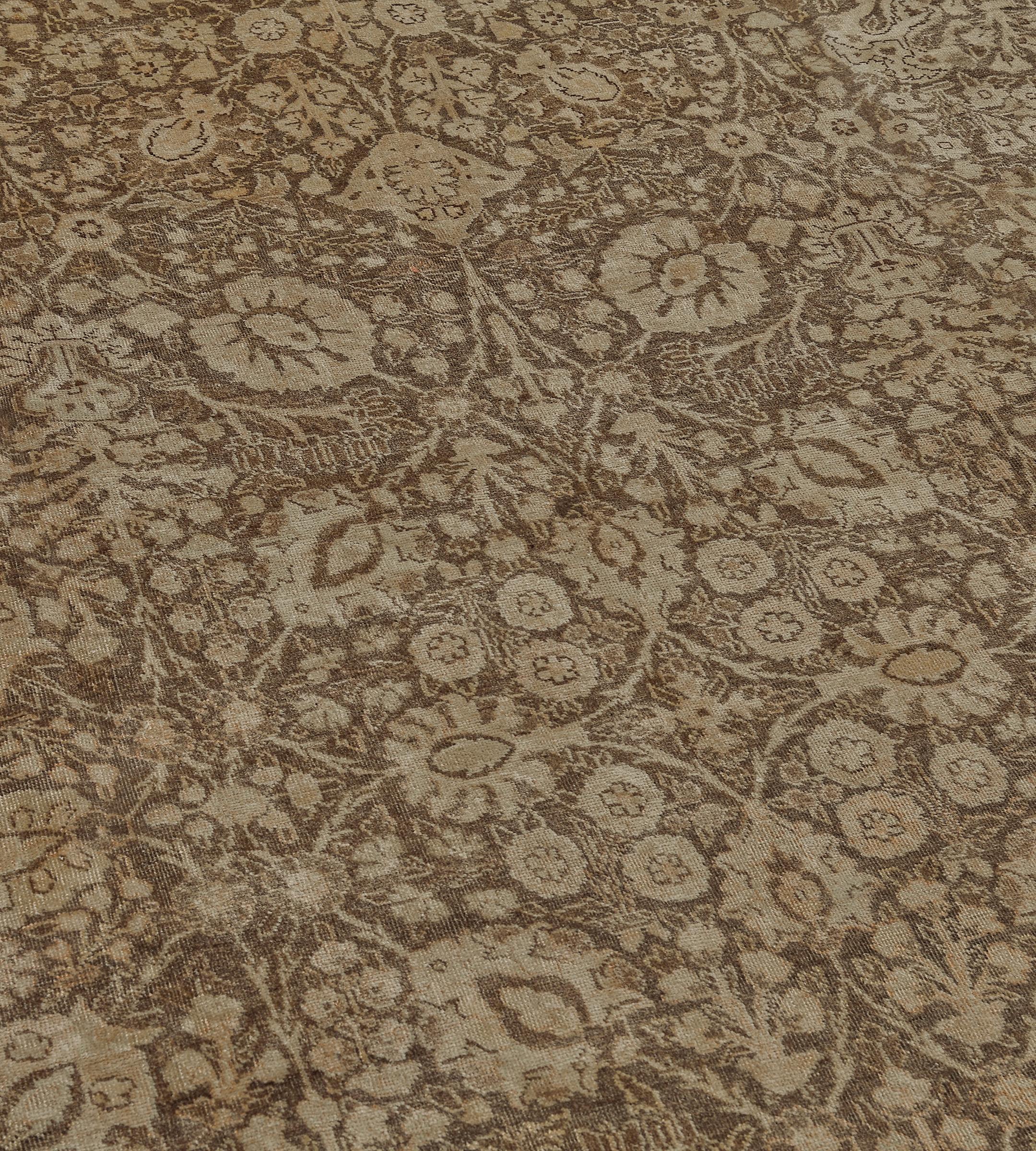Ce tapis persan Tabriz traditionnel tissé à la main a un champ général brun café chaud de vignes de palmettes denses contreposées émettant des fleurs délicates denses et des vignes formant des losanges, dans une bordure ivoire tonale de motifs de