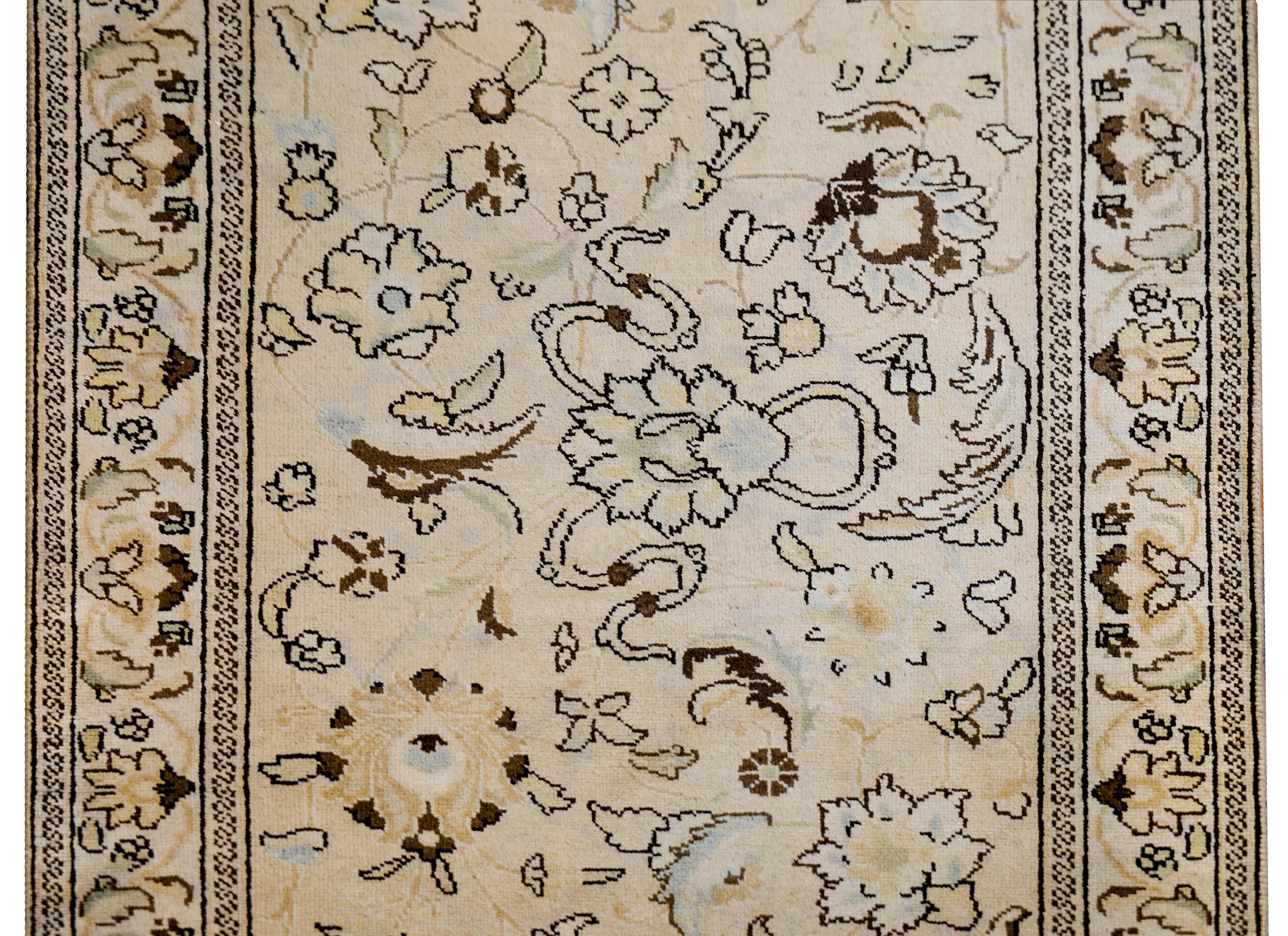 An early 20th century Persian Tabriz runner with a finely rendered large-scale floral and scrolling vine pattern woven in cream, brown, pale indigo, and pale orange vegetable dyed wool. The border is simple, with a central stripe similarly styled to