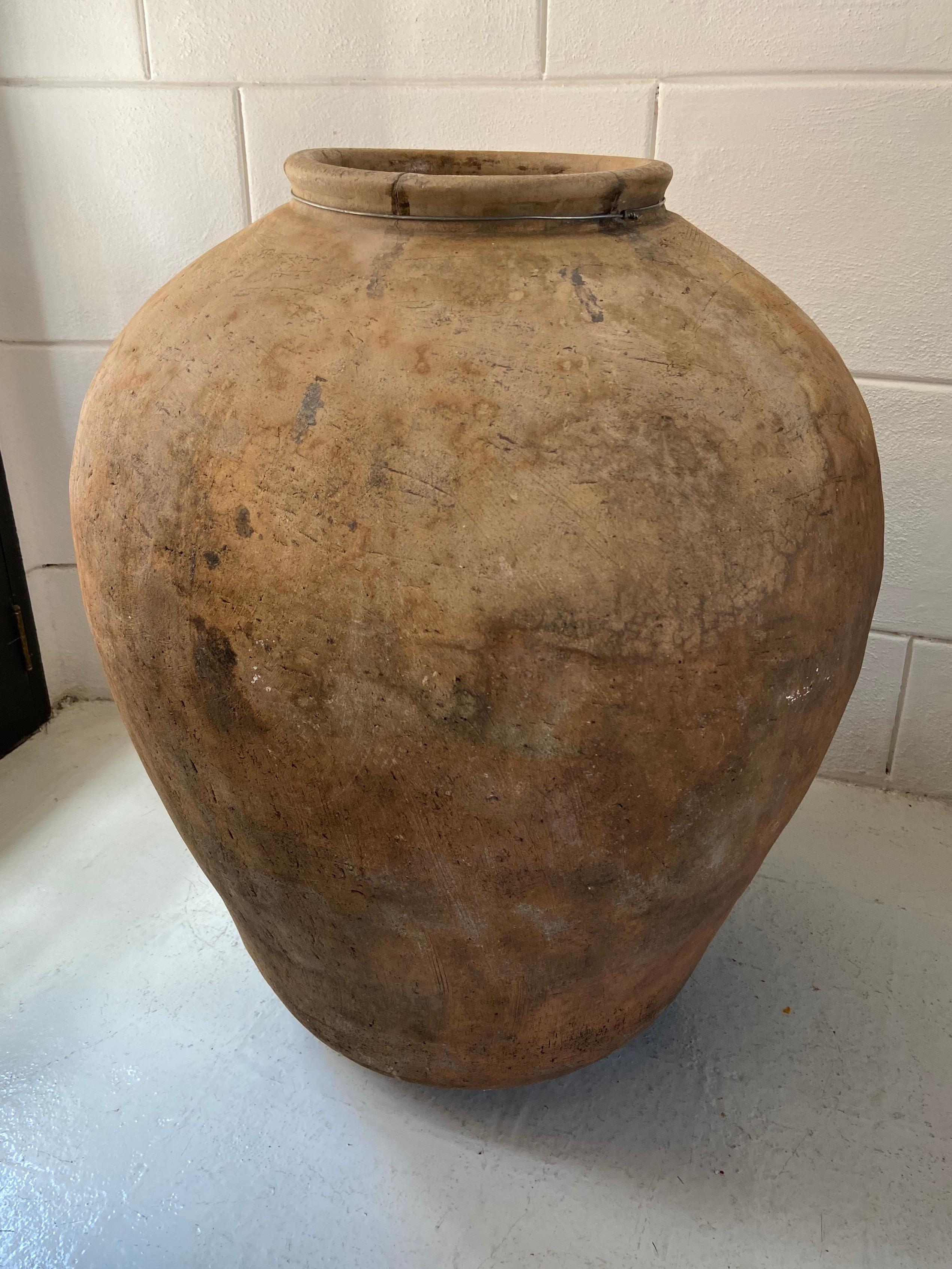 This item is a large early 20th century terracotta pot from Juchitan, Oaxaca. The jar was once used to store water from nearby rivers. The wide and tall form is characteristic of the lower Juchitan region. These massive pots are no longer produced