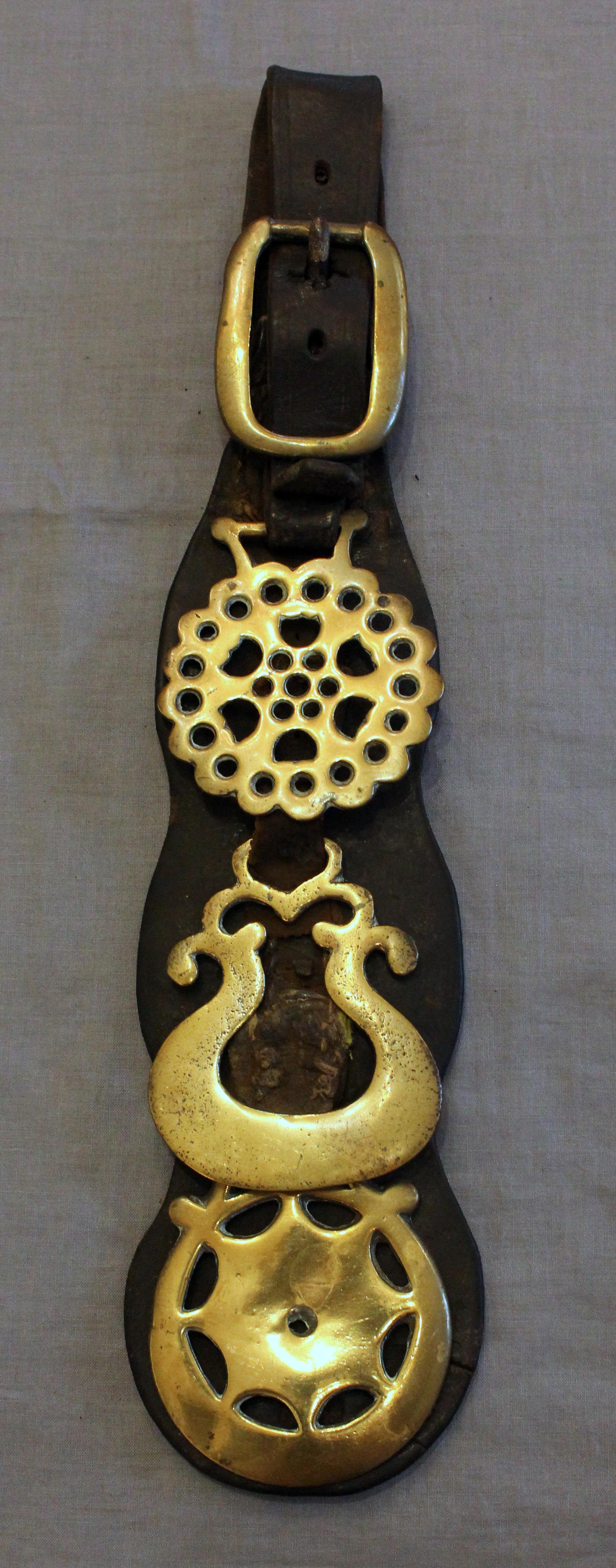 English 3-brass shaped leather horse strap, early 20th century. Three decorative brasses under brass buckle.
15.5