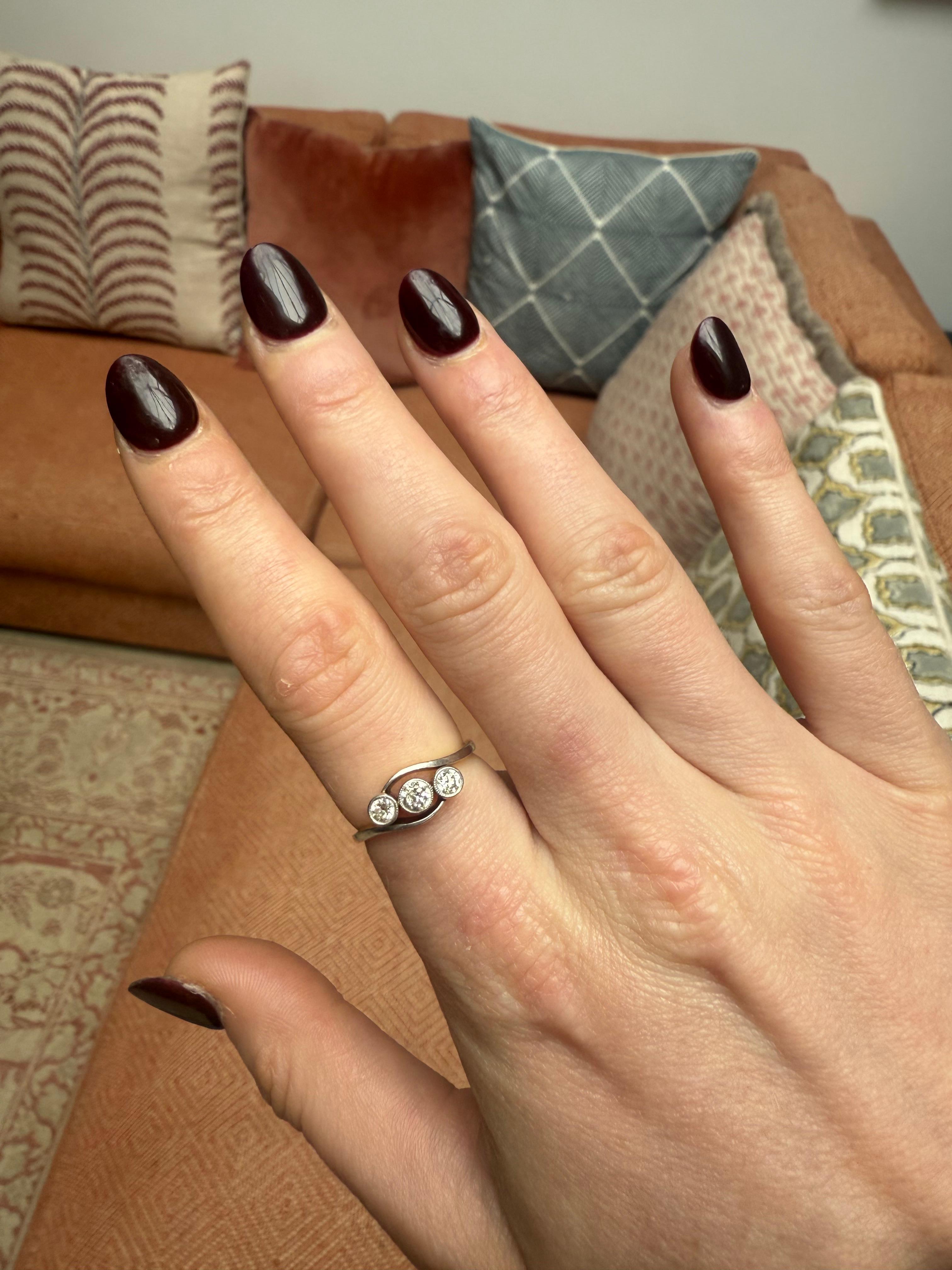 Anello con tre pietre di diamanti antichi di taglio europeo dell'inizio del XX secolo, con incastonatura millegradi e un disegno a vortice che avvolge le pietre. Oro 18 carati con marchio. 

Data: 1929
peso: 3,1 g
Taglia: US 7
Punzoni: oro 18k