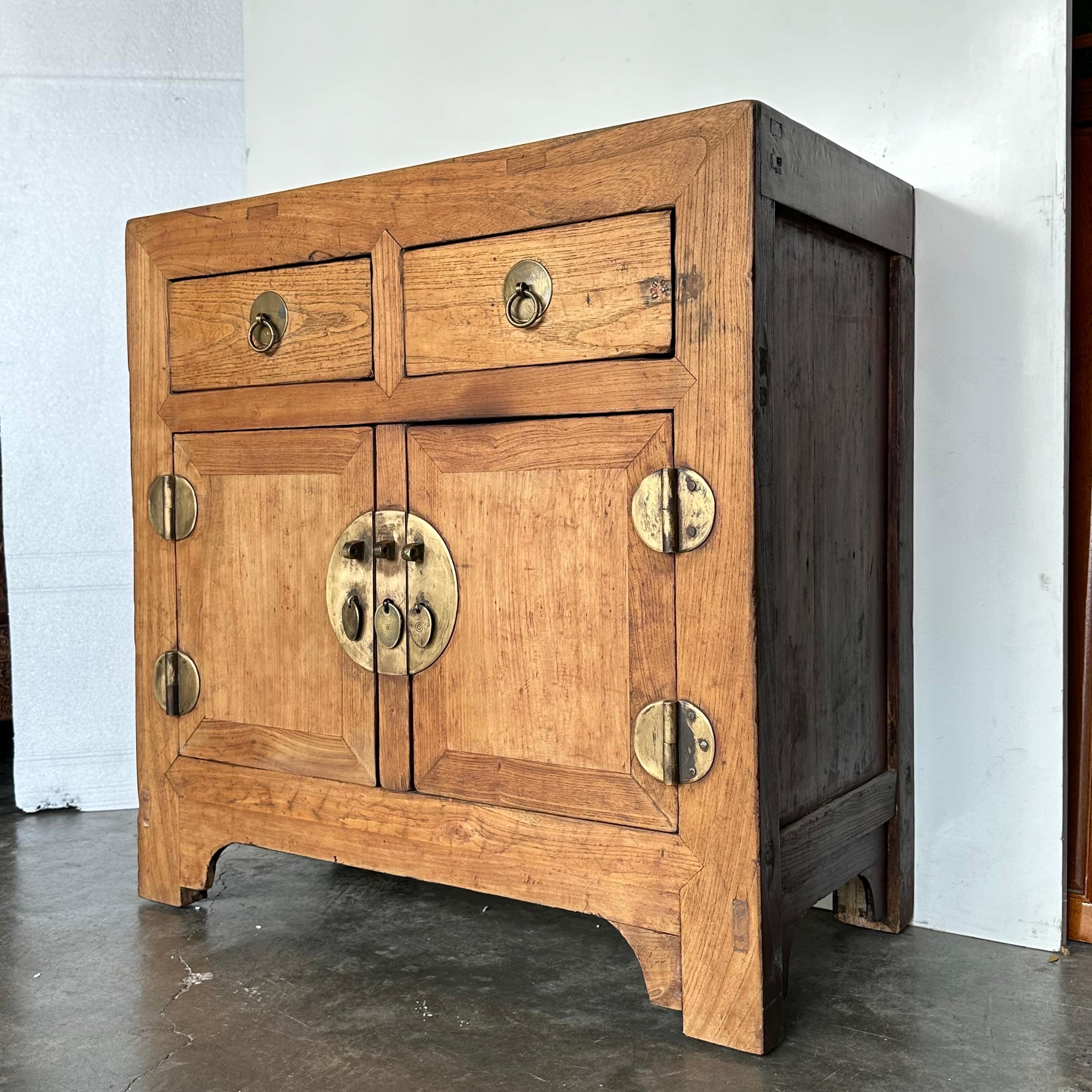 An Elmwood cabinet from Tianjin with beautiful original patina. The round brass plate and hinges on the doors are its original, approximately 3mm thick, while the brass drawer pulls are replacements. The front and top of the cabinet are in a