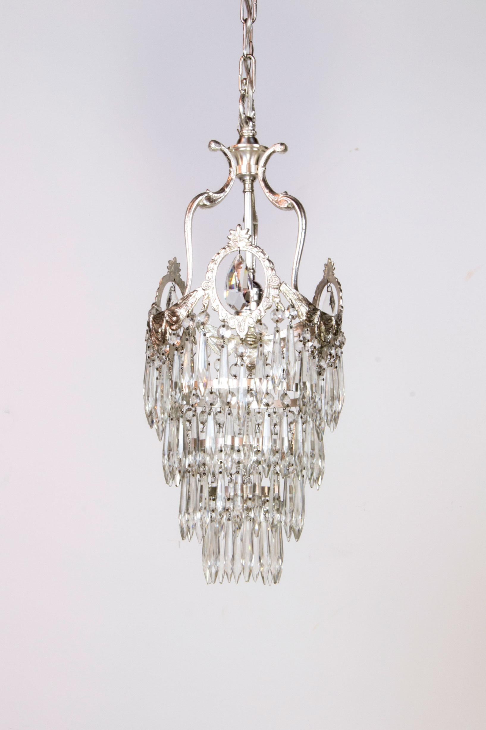 A pair of silver plate fixtures with crystal. sculptural crown with keyhole crystal and tiers of crystals cascading below. Add a touch of glamor to a kitchen, hallway, or even as hanging bedside pendants. Completely restored and rewired, ready to