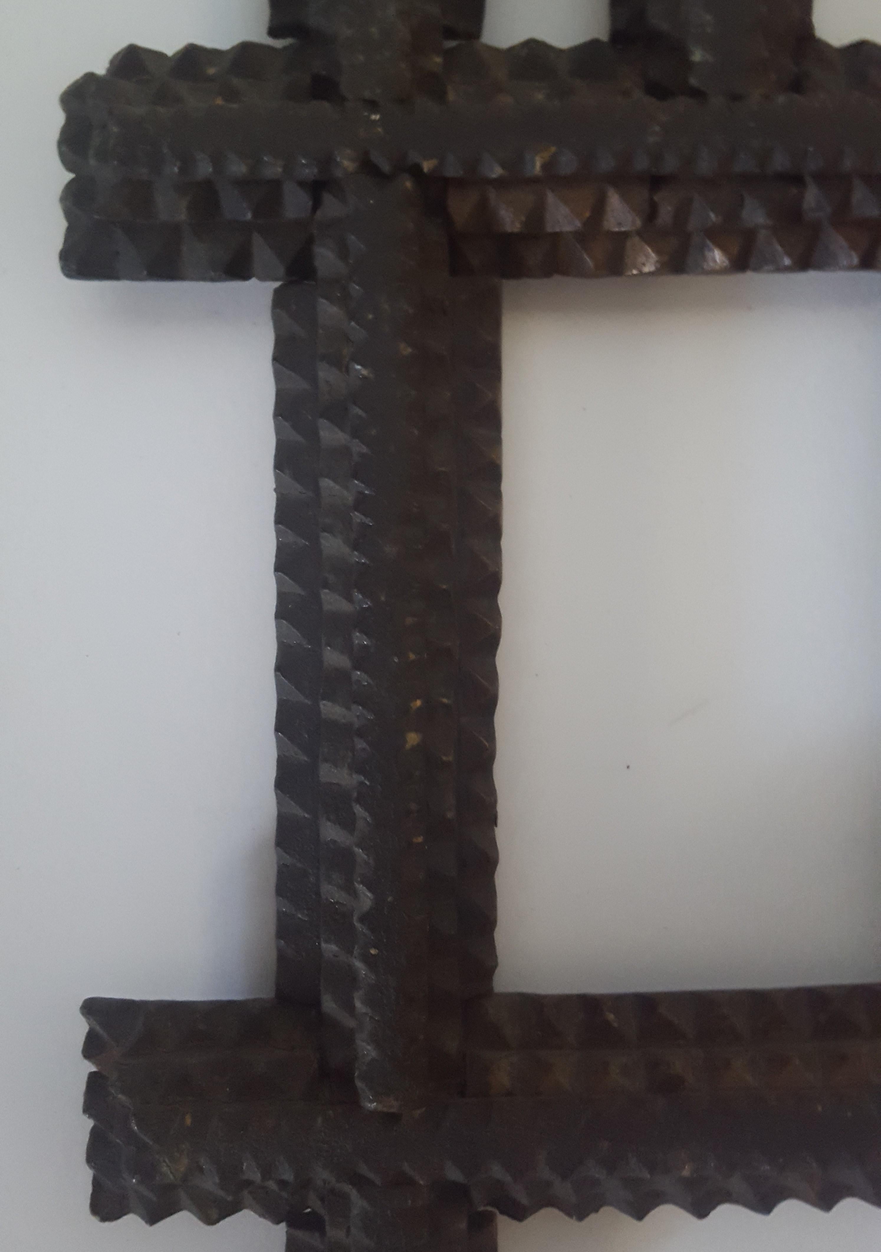 This tramp art picture frame is stained a dark, black/brown. It is made of three built-up layers of thin, scrap wood. Each wooden layer is chip carved in typical, pyramid shaped cuts, creating three photo/picture openings with crossed, extended