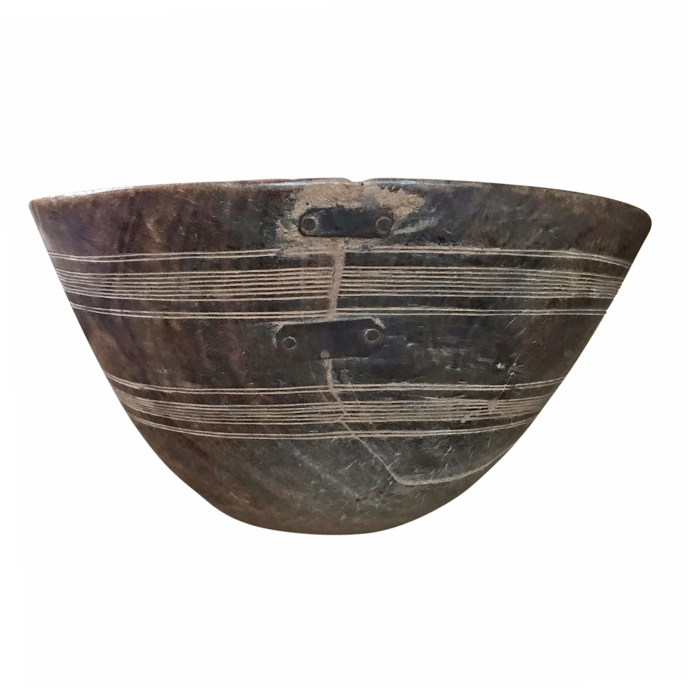 An early 20th century Tuareg bowl carved of a single piece of wood with an incised line pattern around the perimeter, with three beautifully executed repair straps. The Tuareg are nomadic pastoralists who inhabit the Saharan region of Northern