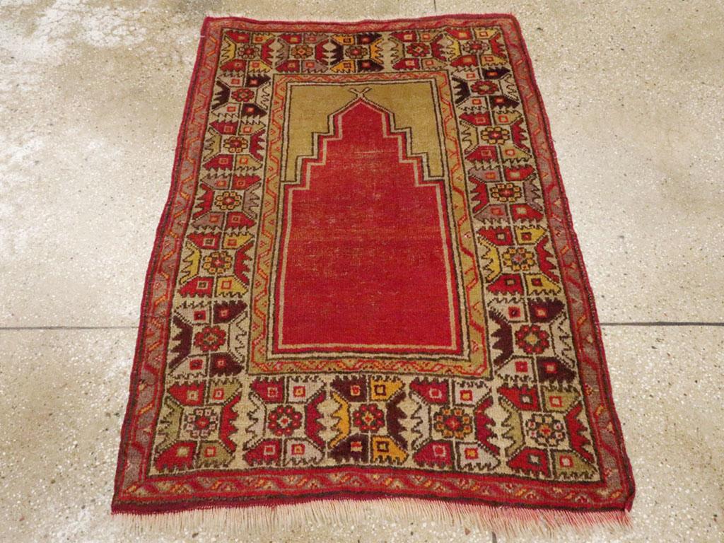 Ein antiker türkisch-anatolischer Vorleger. Das offene rote Nischenfeld steht unter goldgelben, einfarbigen Zwickeln und innerhalb einer alten elfenbeinfarbenen Hauptbordüre mit gezackten, quadratischen Blütenblattrosetten. Der Stil ist