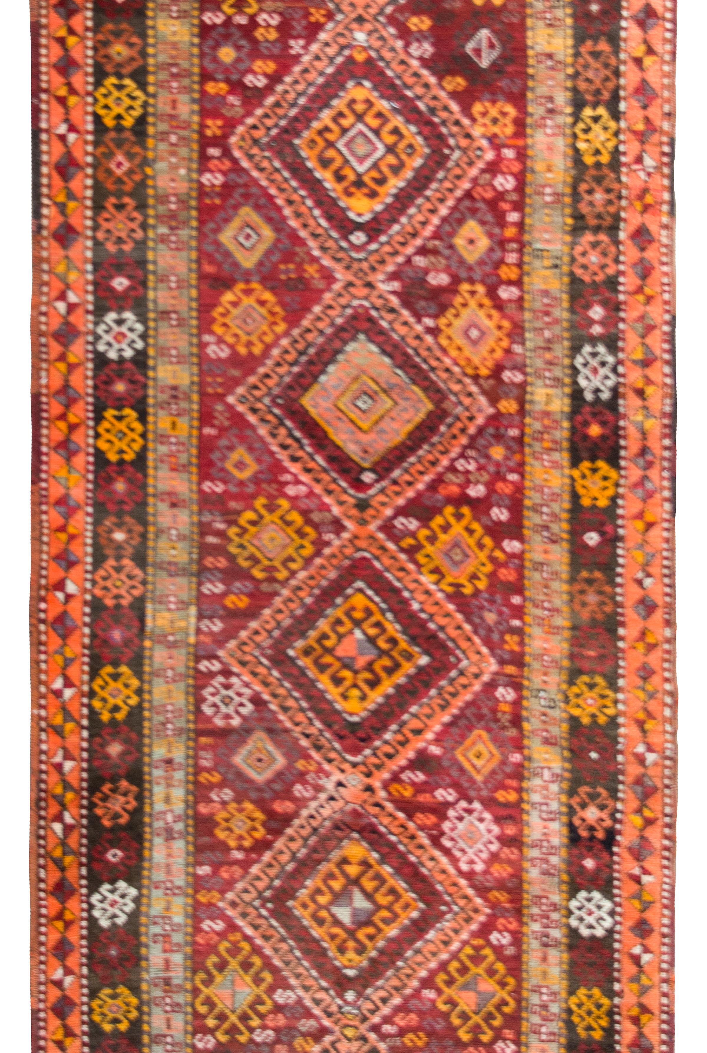 A bold and brilliant early 20th century Turkish Kars rug with several central diamond medallion running the length, and surrounded by field of stylized flowers, all surrounded by a complex border of even more stylized flowers, and all woven in