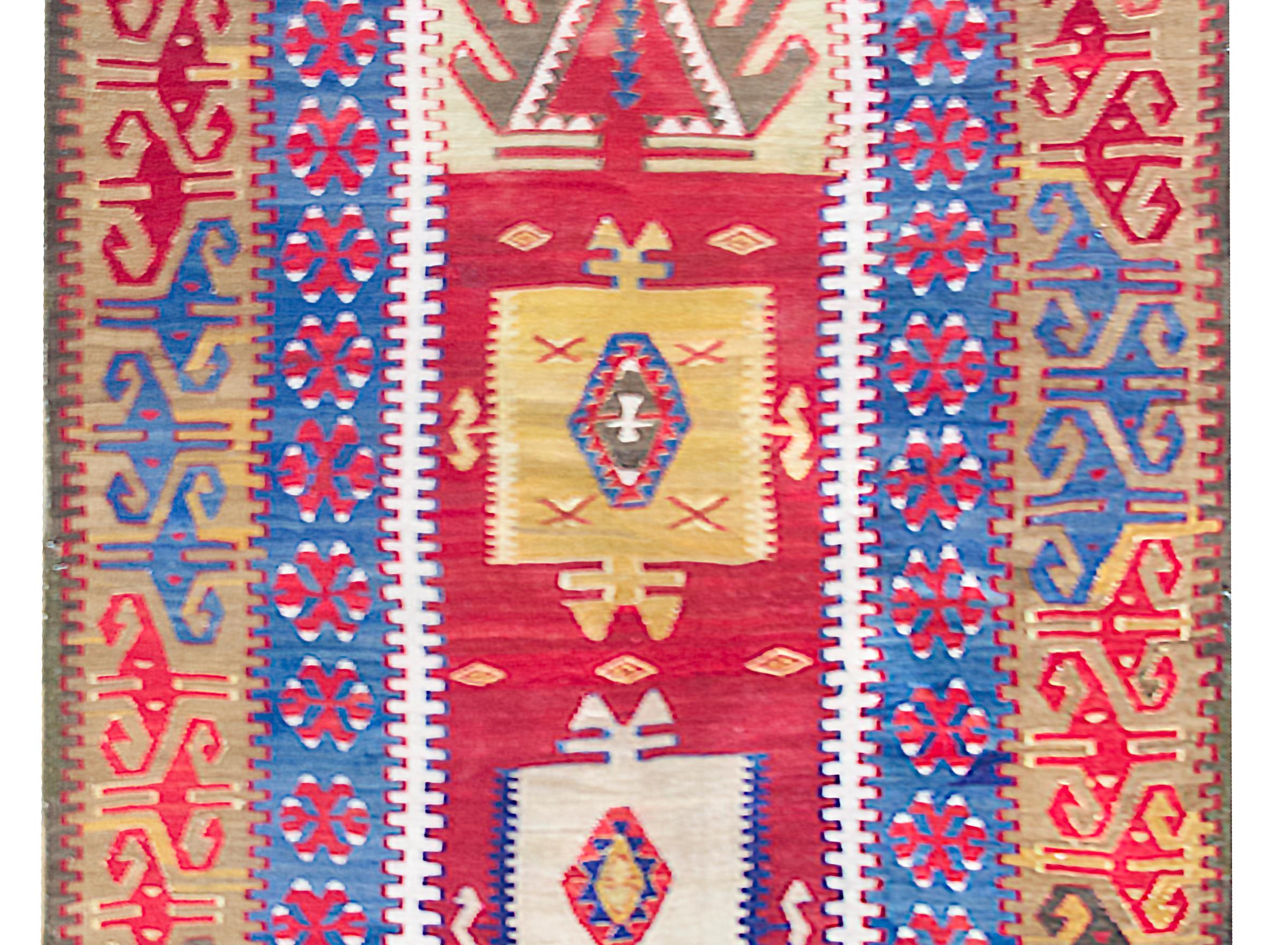 A stunning early 20th century Turkish Konya kilim rug with a fantastic bold tribal pattern containing two large stylized floral medallions amidst a field of more stylized flowers, surrounded by a complex stylized floral border, and all woven in
