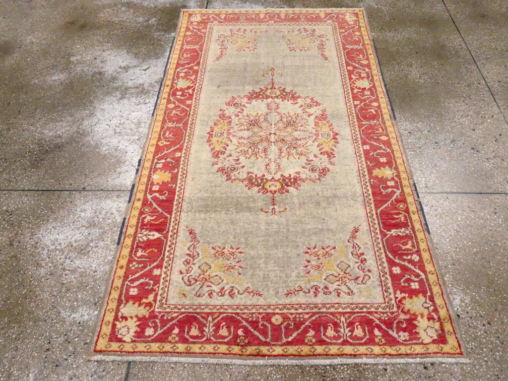 Un ancien tapis d'accent turc Oushak. Un médaillon ovale à symétrie bilatérale en forme de bouquet, avec des coins en guirlande florale, est placé sur le champ ouvert vert pâle et encadré d'une bordure en briques avec une vrille étirée entourant des