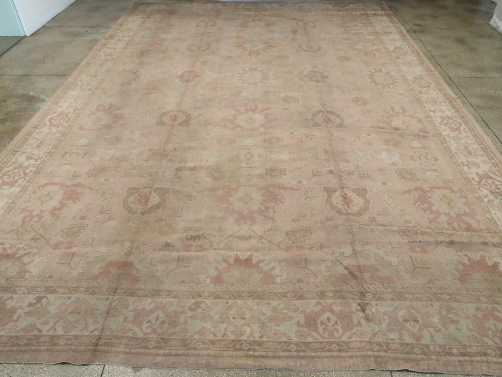 Ein antiker türkischer Oushak-Teppich in Übergröße. Dieser türkische Stadtteppich hat ein fünfspaltiges Muster, das vom klassischen persischen Harshang-Muster mit Palmetten, Zahnradrosetten und dünnen, diagonalen Ranken abgeleitet ist.  Die