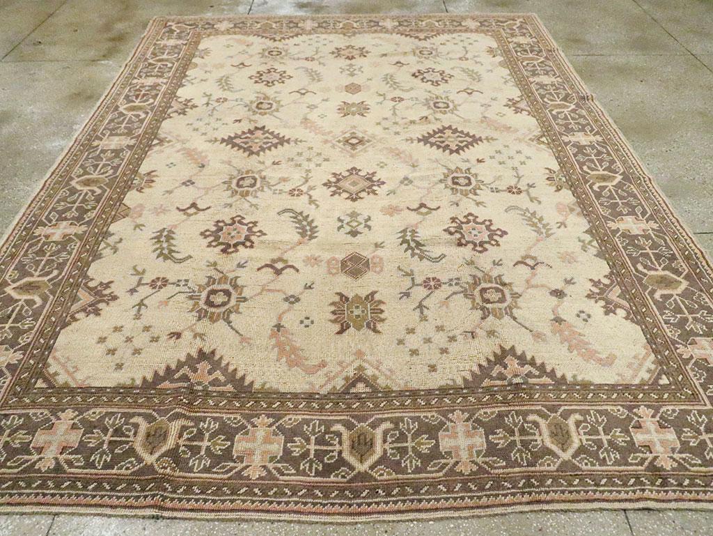 An antique Turkish Oushak room size carpet. This western Turkish town piece has a spacious, genuine allover pattern repeat of snowflakes, sawtooth lozenges and sickle leaves on an off-white ground. The boldly abstract turtle palmette and octagon