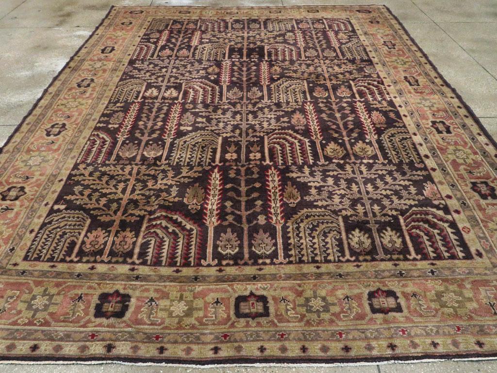 An antique Turkish Oushak room size carpet. This western Turkish workshop Oushak carpet adheres closely to Persian Heriz sources with its dark blue ground displaying traditional cypresses, plane trees, and weeping willows, along with smaller bushy