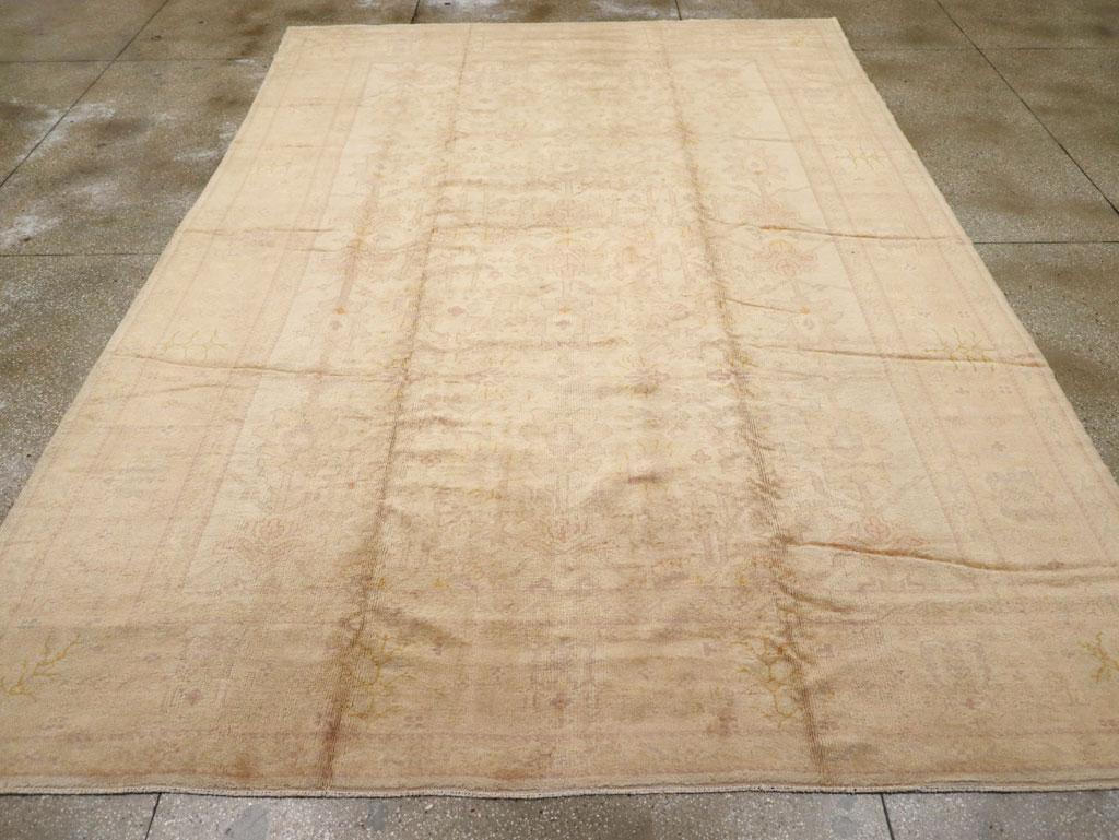 An antique Turkish Oushak carpet. The ambiance is mellow on this west Anatolian workshop carpet with an all-wool construction. Old ivory and straw yellow help to define the isolated floral motives in the field. This carpet is all about the softness