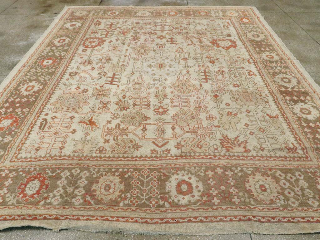 Tapis ancien turc de type Oushak, de la taille d'une pièce. Le champ en vieil ivoire de ce tapis de ville de l'ouest de la Turquie présente une version grossièrement dessinée du motif Harshang, avec des palmettes déchiquetées et des sections de