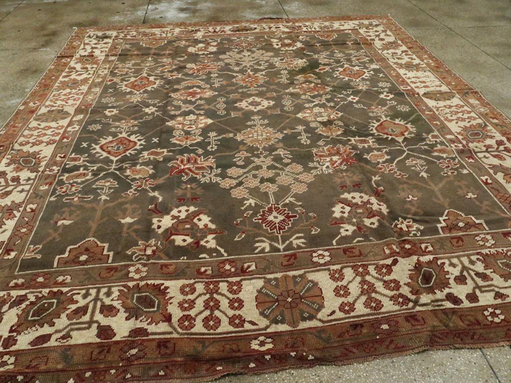 Ein antiker türkischer Oushak-Teppich in Zimmergröße. Eindeutig im persischen Designmodus zeigt dieser westtürkische Werkstattteppich eine locker wiedergegebene Version des Harshang-Musters mit zackigen Palmetten, abgeflachten Rosetten, Blumenarrays