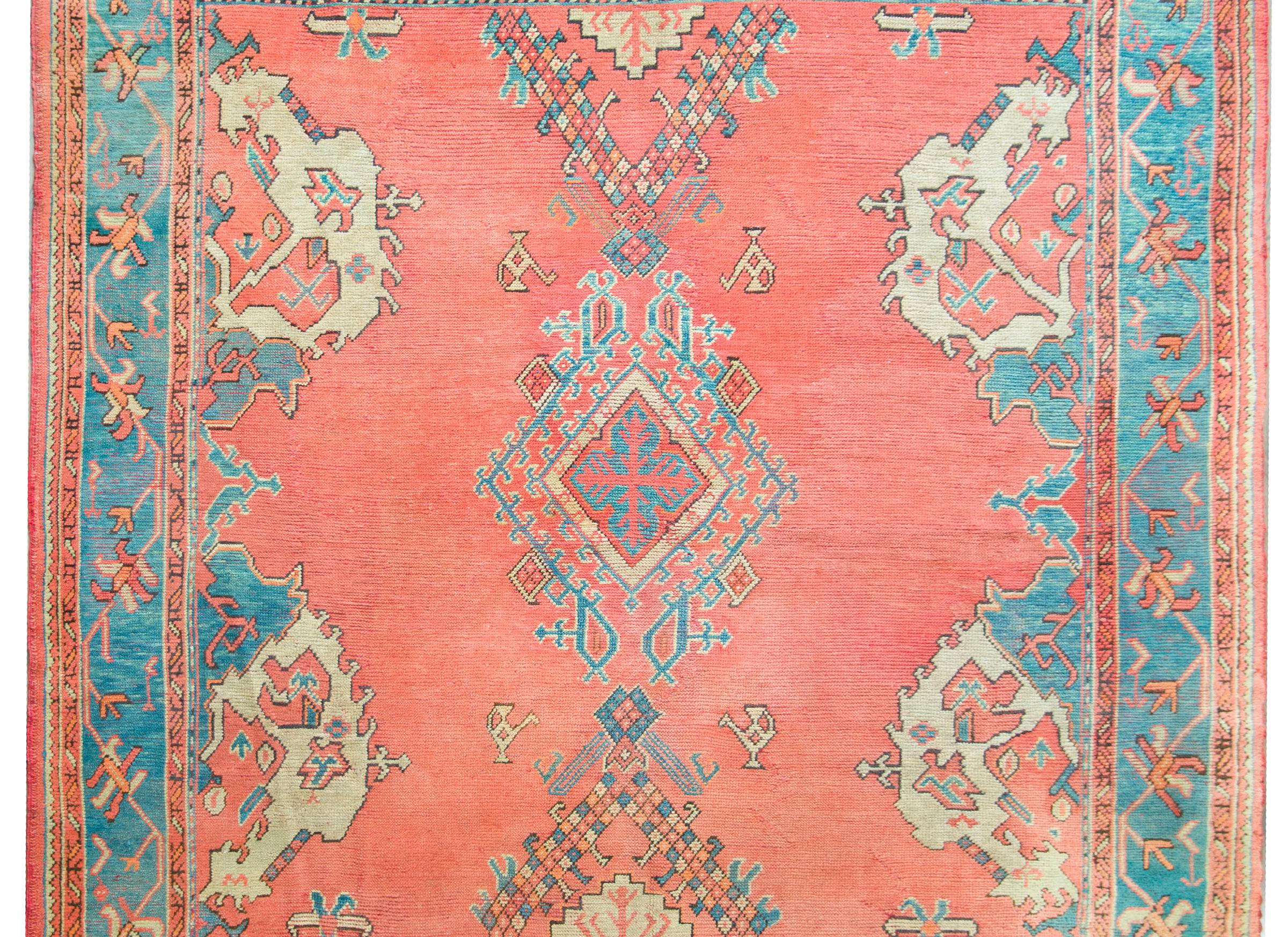 An incredible and brilliant early 20th century Turkish Oushak rug with the most wonderful geometric and stylized floral patterns woven in turquoise, cream, and coral, and set against a gorgeous coral background. The border is wonderful, with