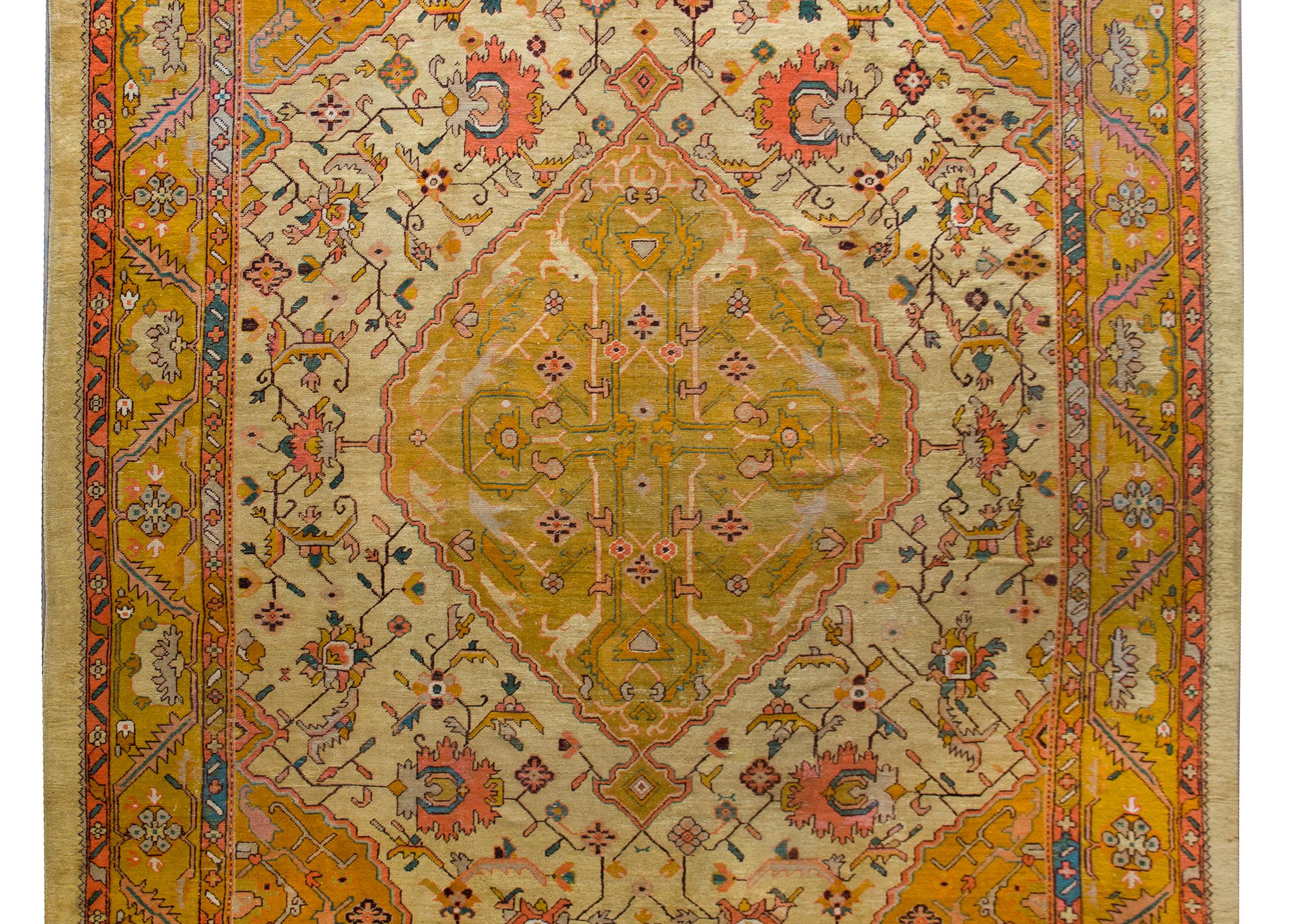 A remarkable early 20th century Turkish Oushak rug with a fabulous central medallion with a stylized floral cross, living amidst a field of even more stylized flowers and scrolling vines, and surrounded by a border with a wide central floral stripe