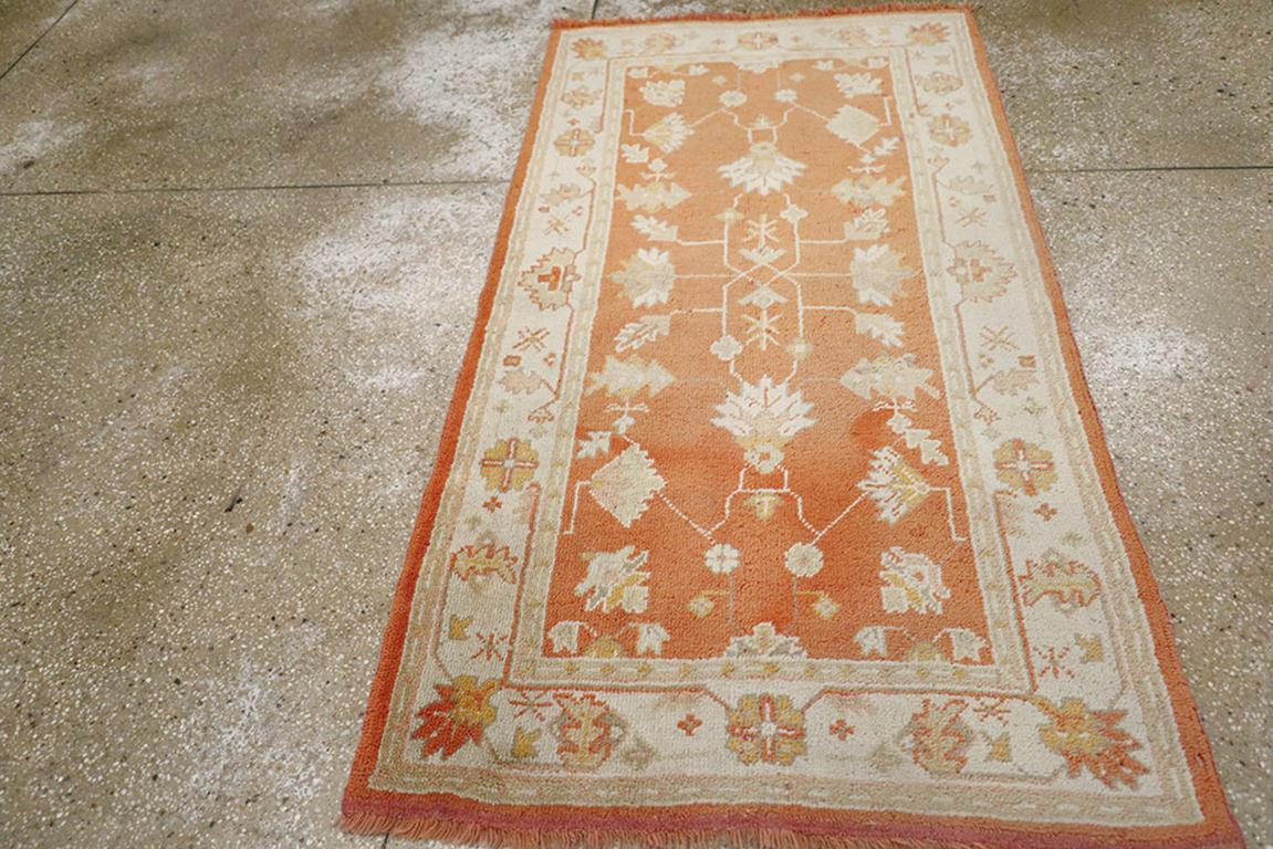 Un tappeto Oushak turco vintage. Il caldo terreno color salmone e ruggine mostra una vasta gamma di palmette, foglie e viti corte e dritte. Il bordo avorio continua a essere ben distanziato con palmette geometriche e lunghi e sottili viticci