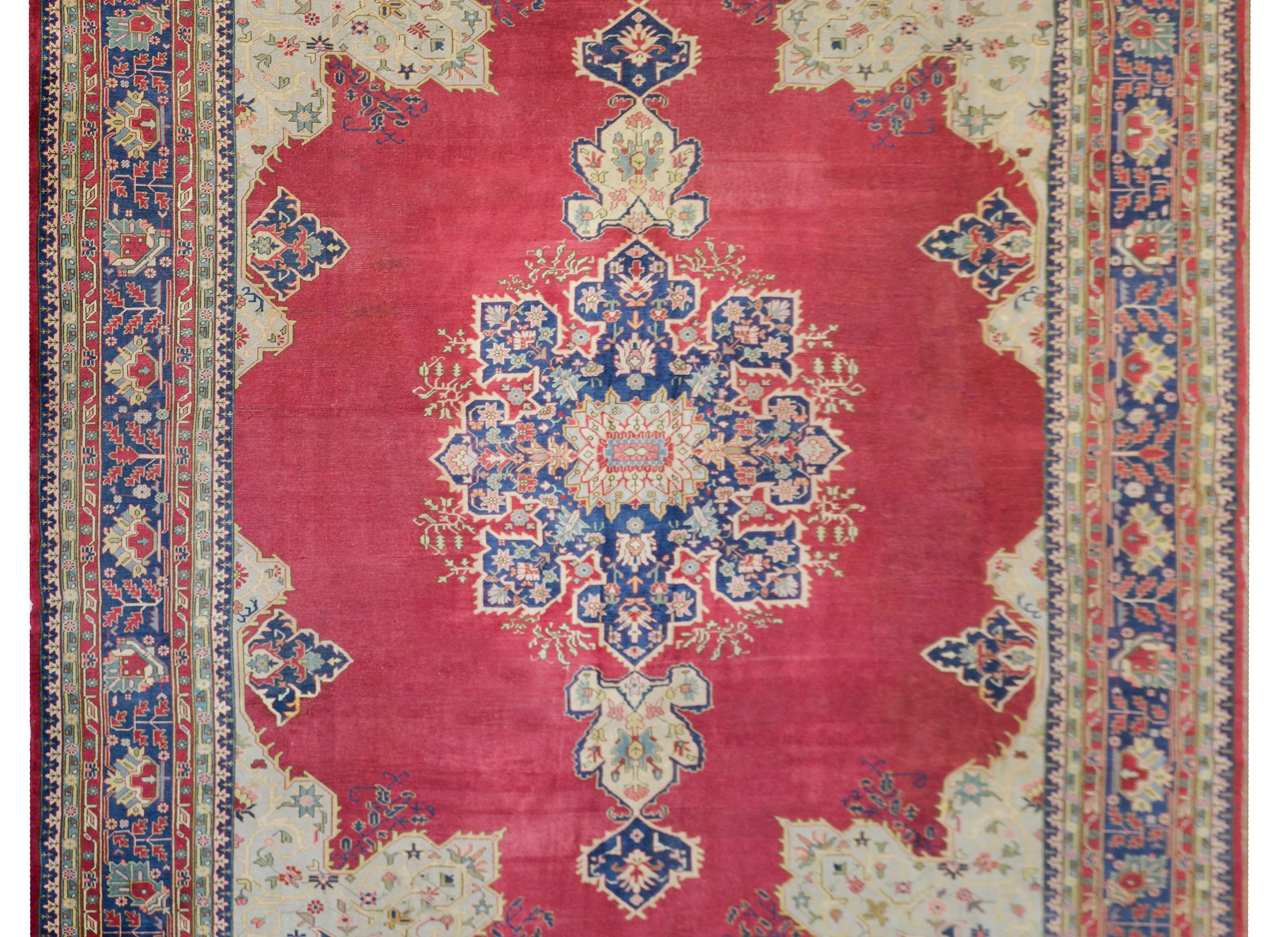 A bold early 20th century Turkish Sparta Serapi rug with a gorgeous large scale eight-lobed floral medallion woven in indigo, pink, and cream, against a rich cranberry field, and surrounded by a wonderful complex floral and petite scrolling vine