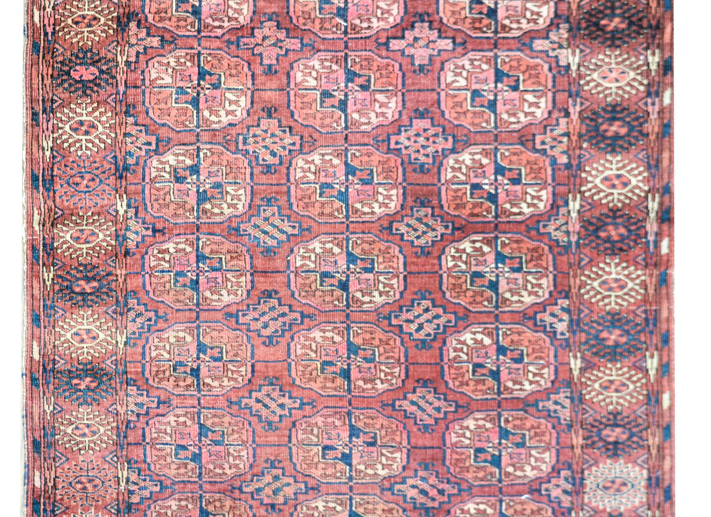 An early 20th century Turkmen Tekke rug with an all-over pattern of multi-colored medallions, each with a stylized floral pattern and woven in orange, white, indigo and crimson. The border is fantastic with several stylized floral patterns.