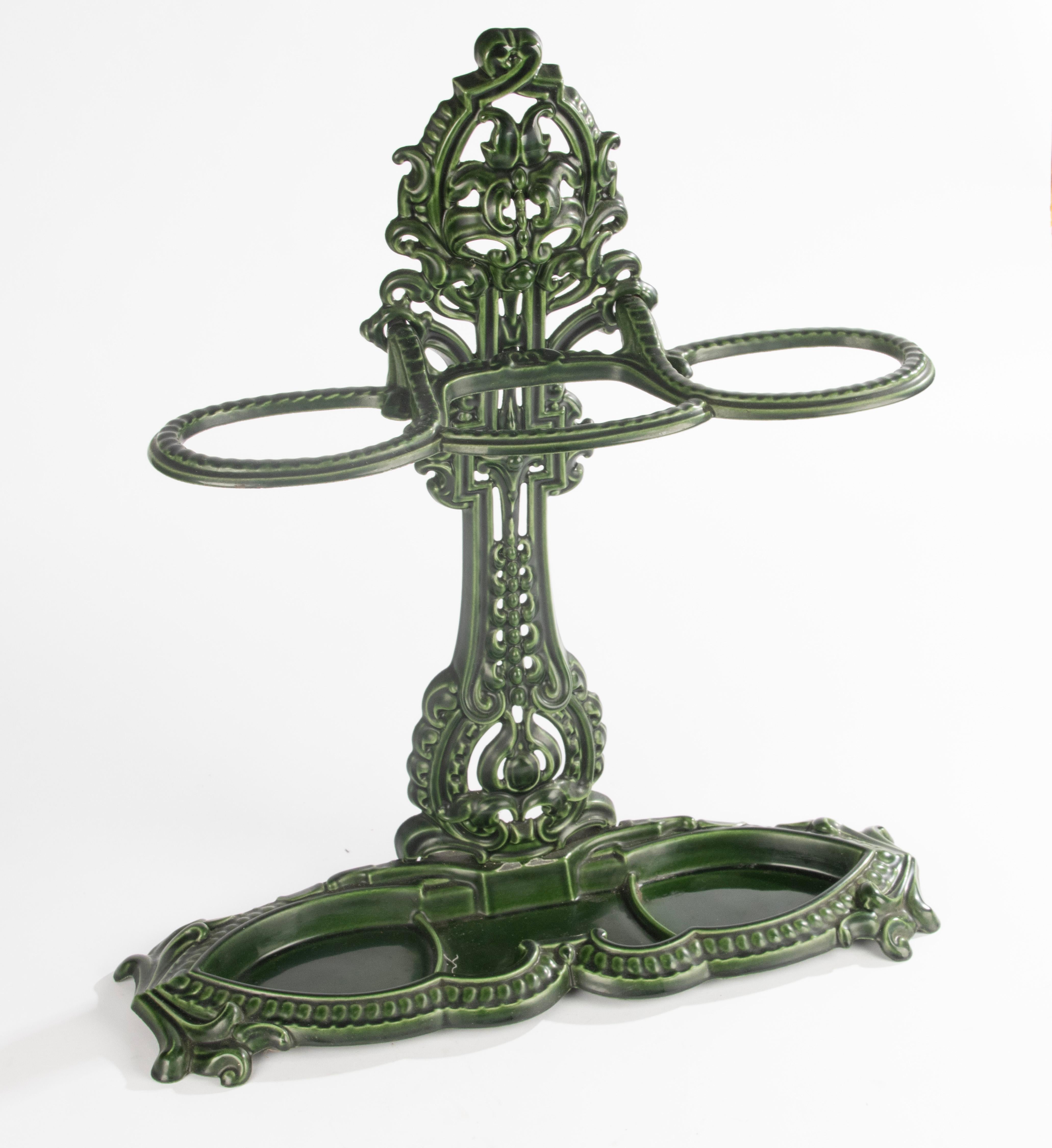 An elegant French umbrella stand dating from circa 1900, crafted in cast iron and finished with a deep green enamel coating. The piece features intricate openwork decoration in a classical style, typical of the period.
The stand is both decorative