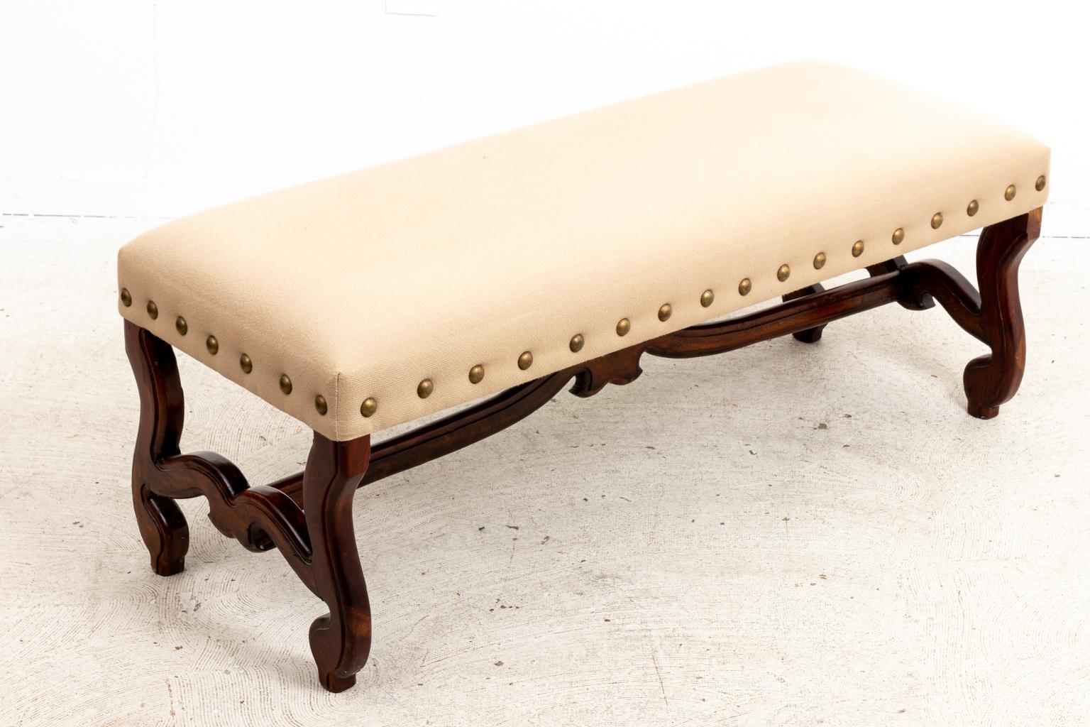 Circa early 20th century upholstered Continental style bench with metal nail head trim and scrolled leg base. The piece also features a bottom cross stretcher with scrolled detail. Please note of wear consistent with age including minor finish loss