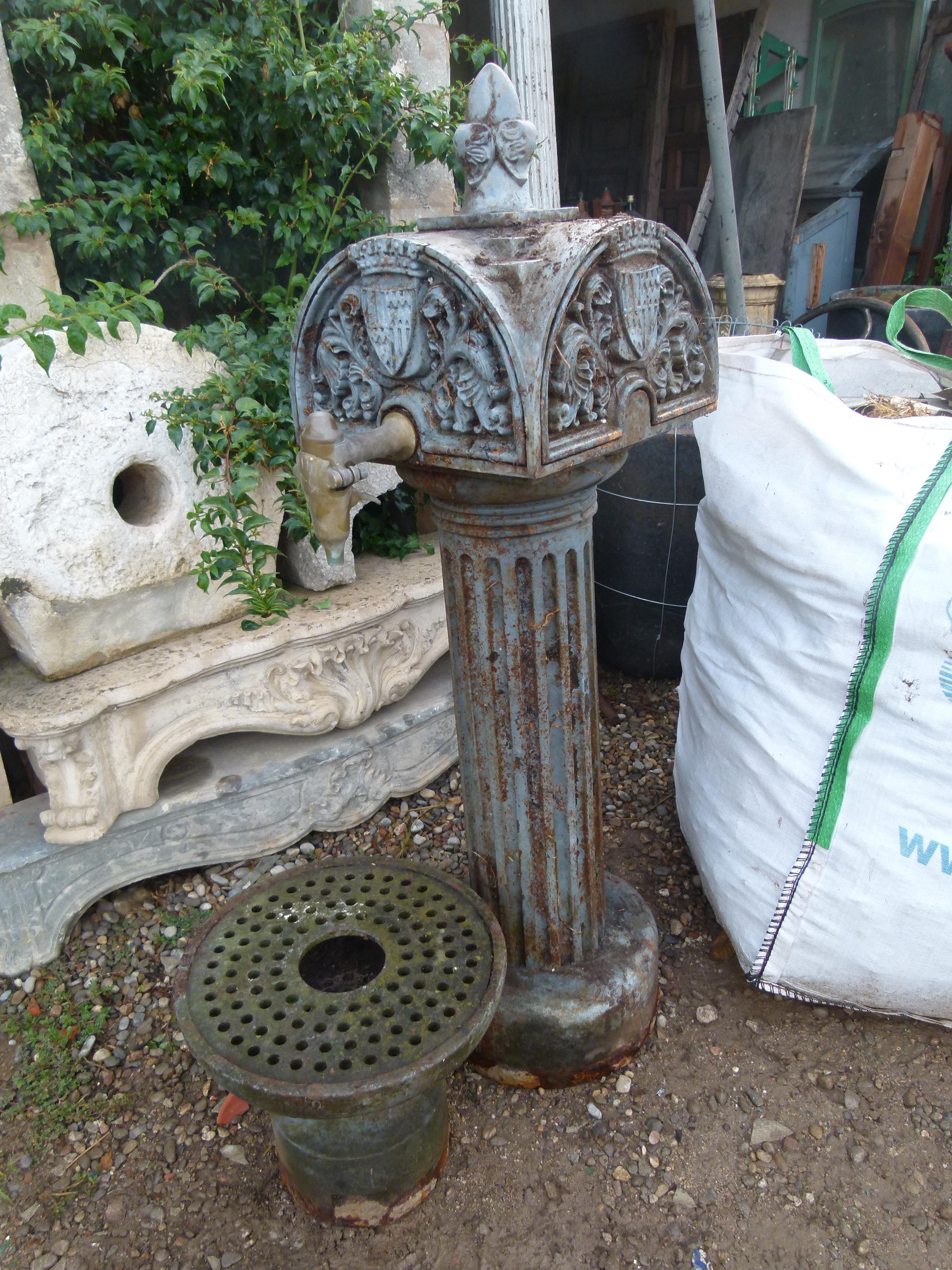 Early 20th Century Urban Cast Iron Fountain with a low-lying sink. It comprises a column that supports a square structure and presents, on each face, a semicircular profile crowned with a pinion and with the shield of the city of Badalona (Spain).