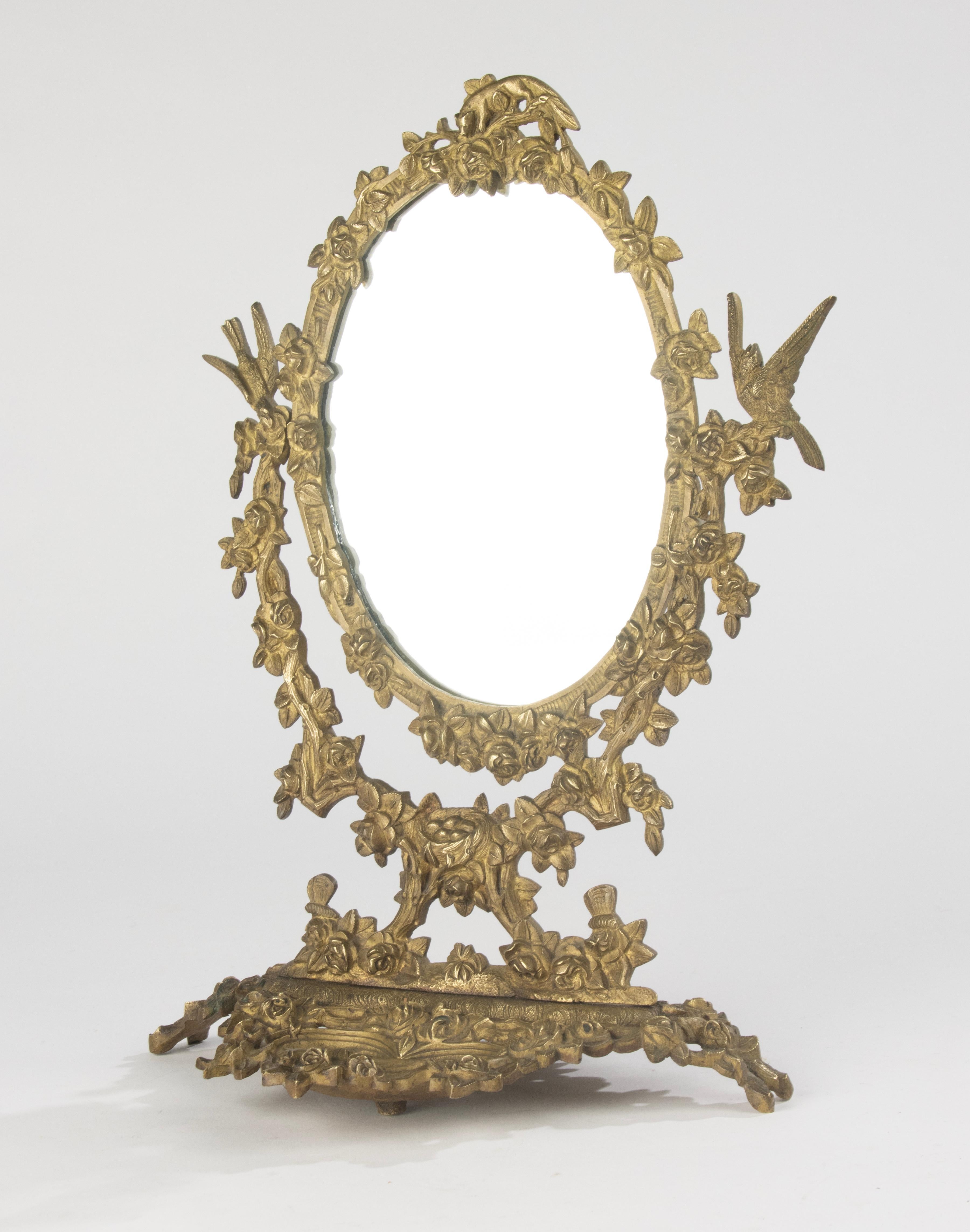 Magnifique miroir de courtoisie en bronze, vers 1910-1920. Ce miroir inclinable finement détaillé présente un cadre richement décoré d'oiseaux, de roses et de motifs naturalistes. Le miroir ovale est placé dans une base sculpturale avec une