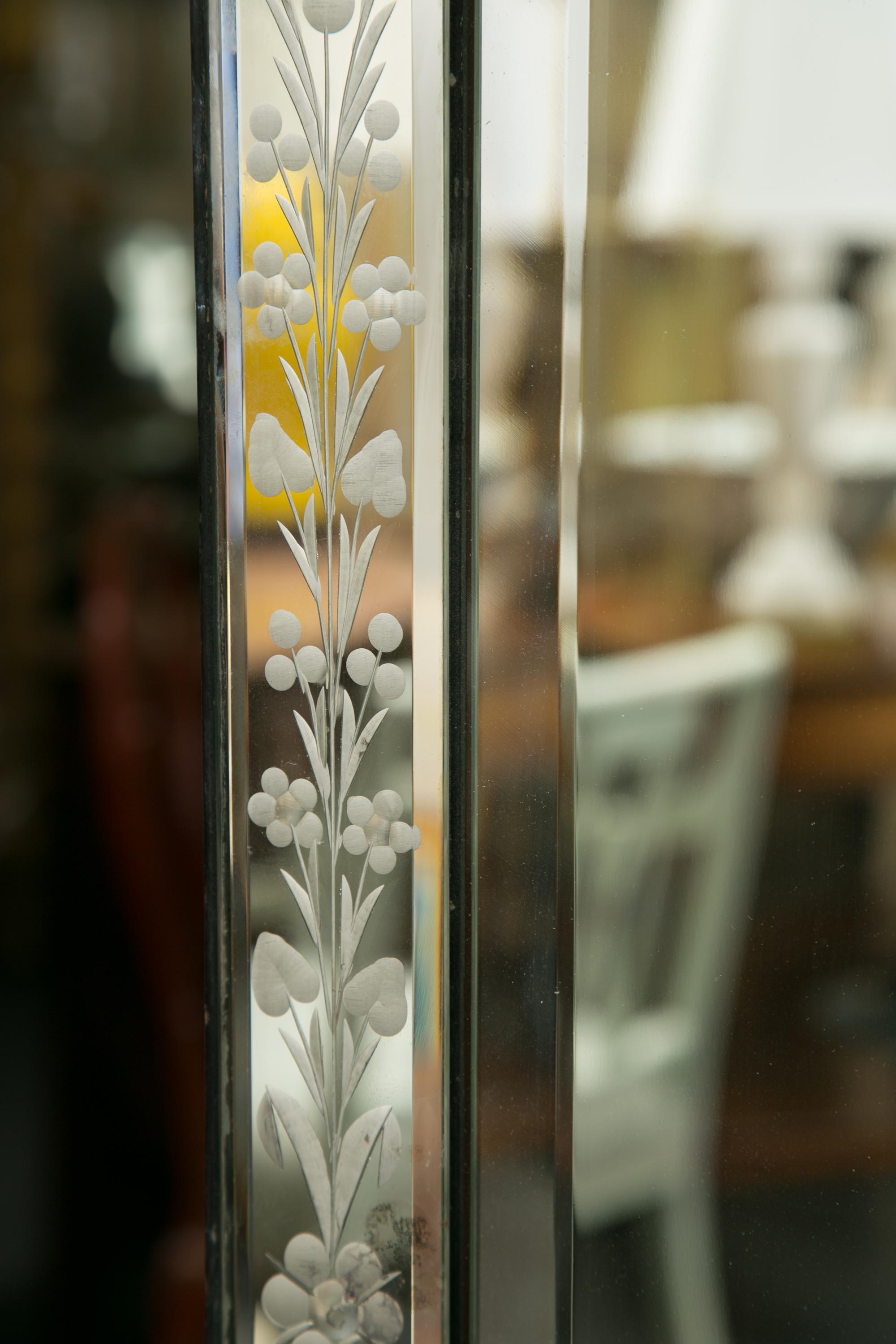 This is a Classic example of a Venetian mirror. There a shaped decorative cornice over a mirror plate surrounded by an etched mirror frame with applied glass corners, circa 1920.