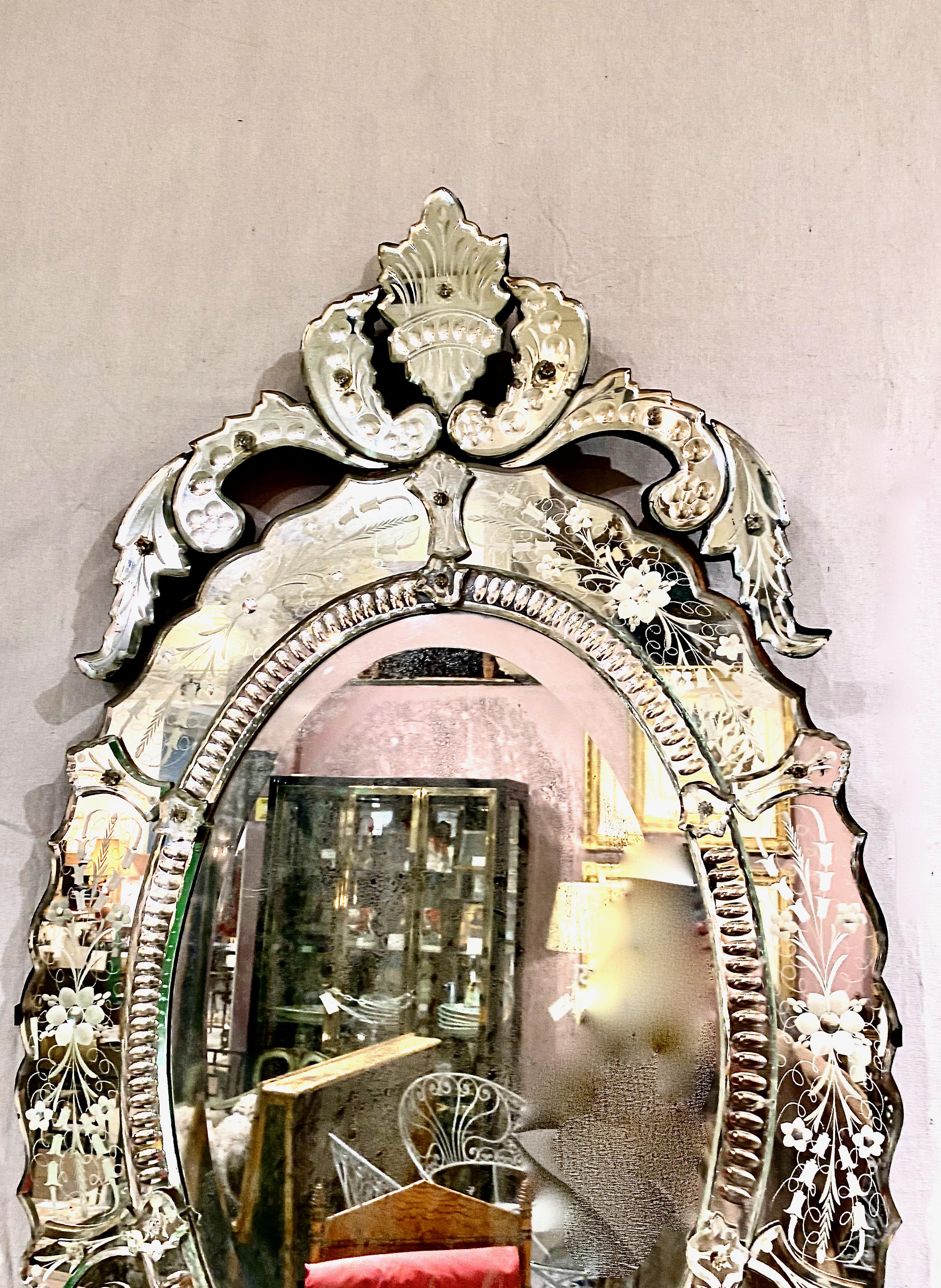 This is a good example of an early 20th century Oval Venetian mirror that is beautifully detailed with a cut scrolling and etched mirror surrounding the central mirror plate. the oval body is surmounted by a cut acanthus leaf scrolling crown. All