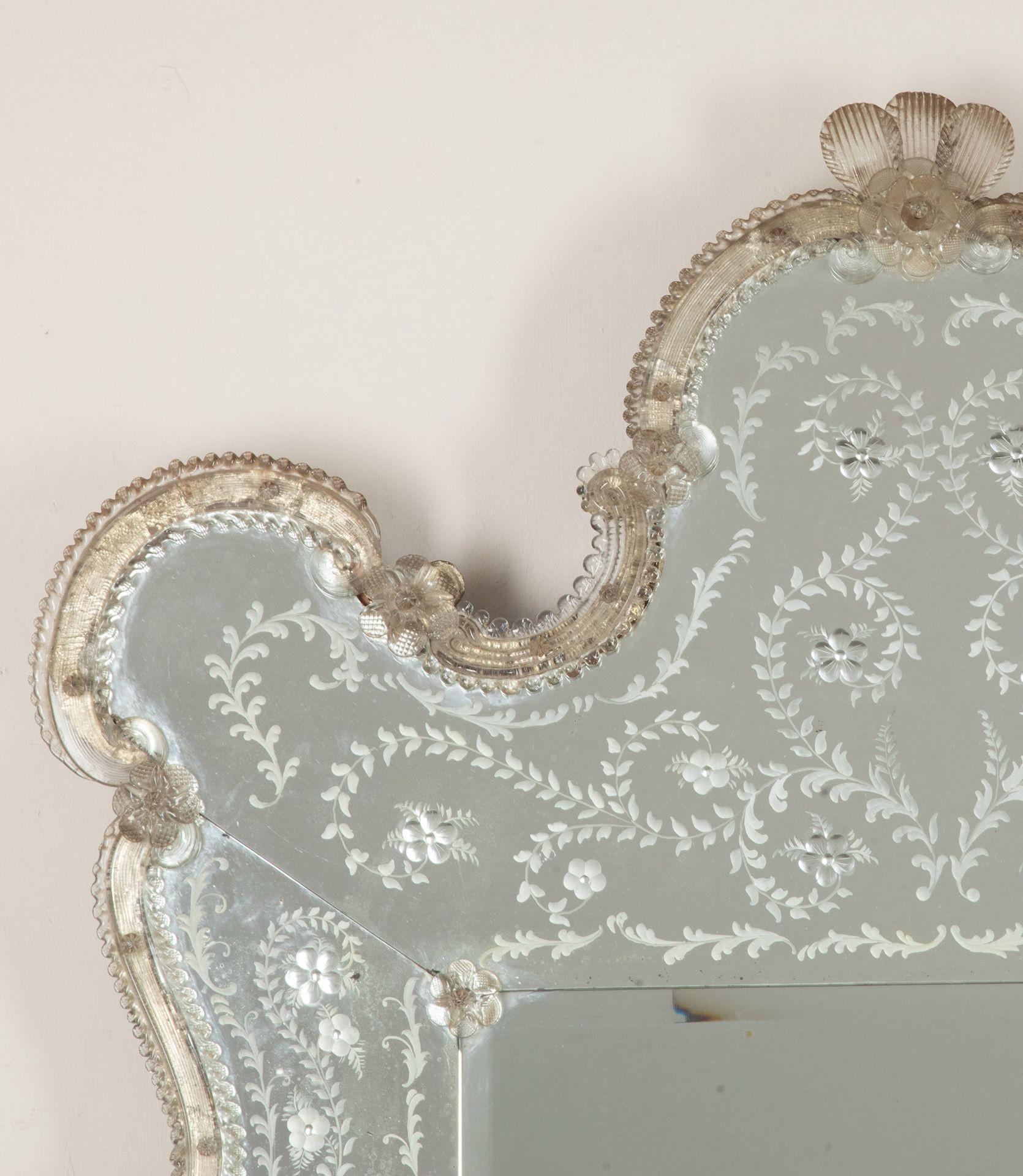 Ein sehr eleganter und ungewöhnlicher Spiegel aus venezianischem Murano-Glas in Form einer Jakobsmuschel aus dem frühen 20. Wunderschön geätzte Randplatten umgeben die originale Spiegelplatte. Mit zarten Perlen- und Blumenelementen an der Bordüre.