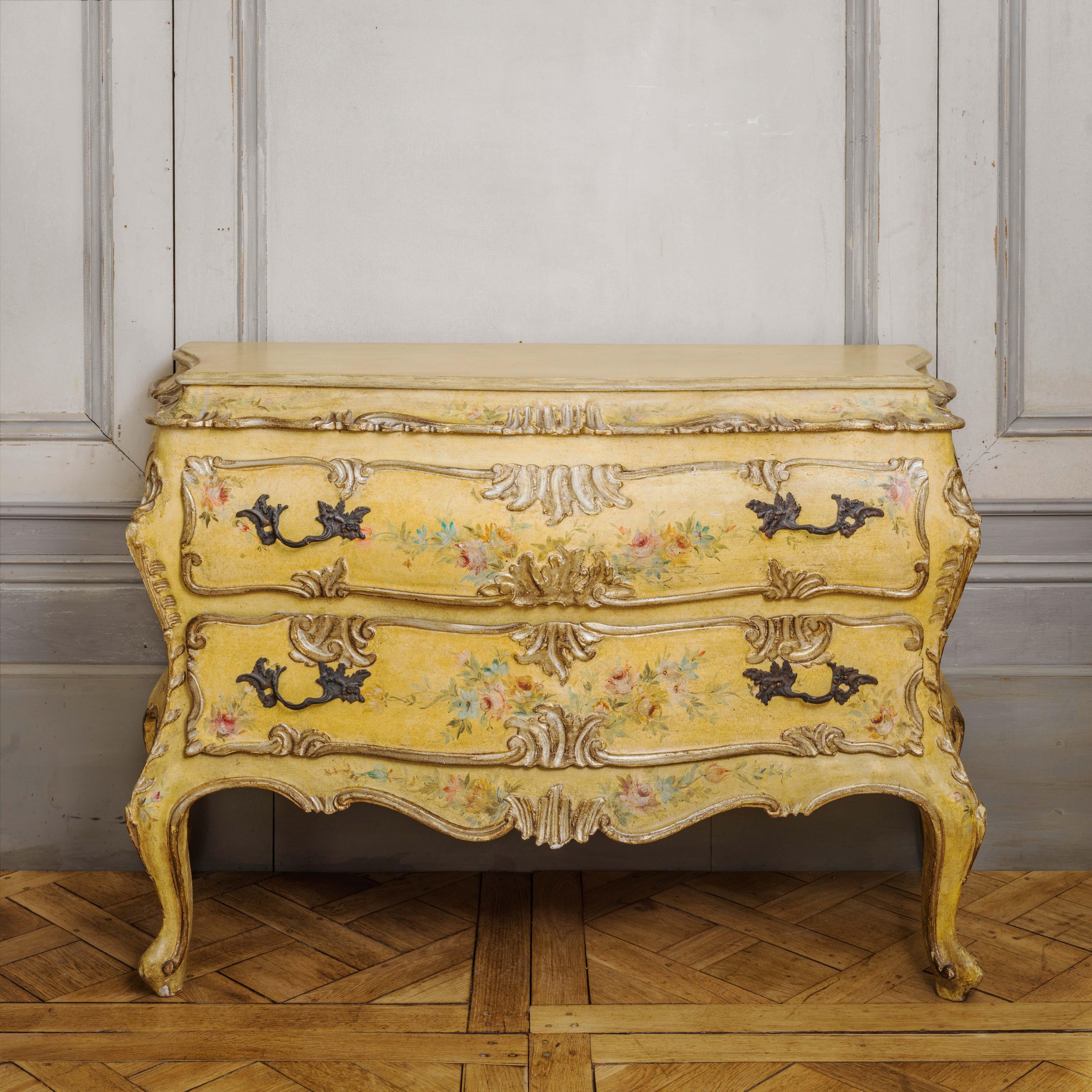 An early 20th century Italian chest of drawers, bombe shape and hand-painted depicting floral motifs in the Venetian style on a sunny yellow background with gilded highlights.