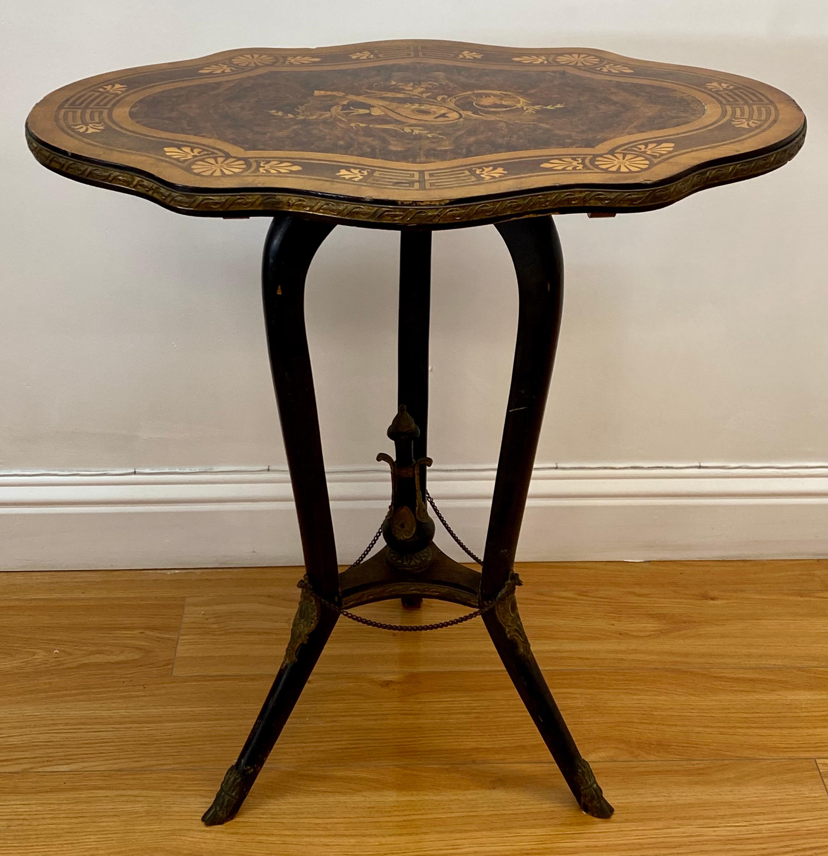 Early 20th century Victorian European walnut inlaid tilt top table c.1900

The ebonized legs and center finial show brass mounts

The hoofed feet also have brass mounts 

A fine inlaid table with musical instruments motif

The table does