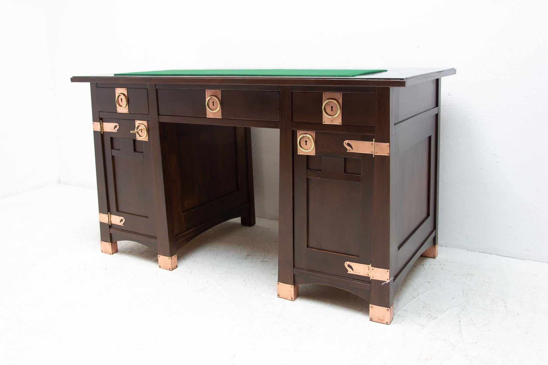 This luxurious-looking Art Nouveau writing desk was made in about 1910 in the former Austria-Hungary. It is made of oak wood. The table top is covered with green plush in the front. All original metal decorative parts were professionally cleaned,