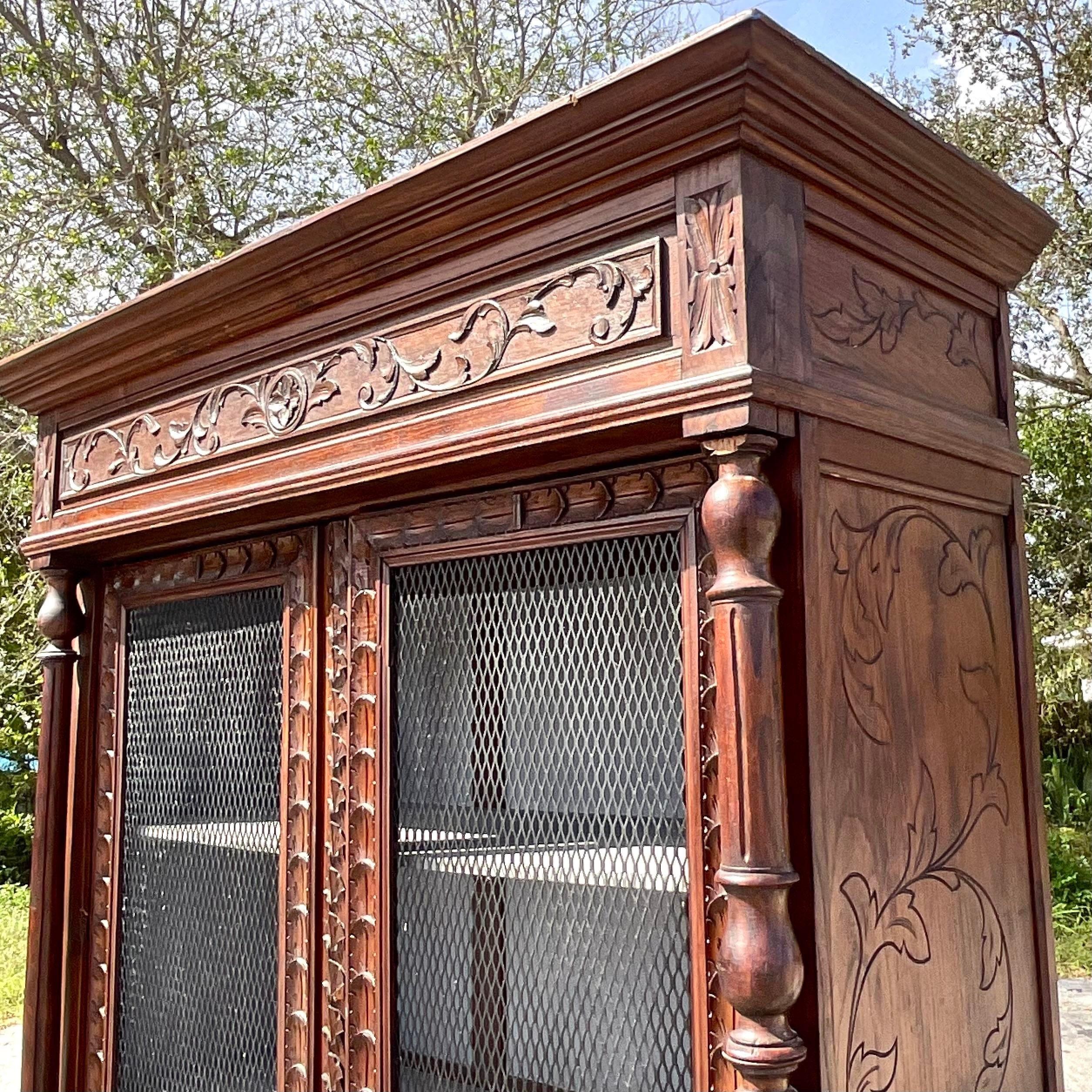 A fantastic vintage Boho display cabinet. A beautifully hand carved cabinet with inset wire mesh door. Lots of great interior space. Acquired from a Miami estate.