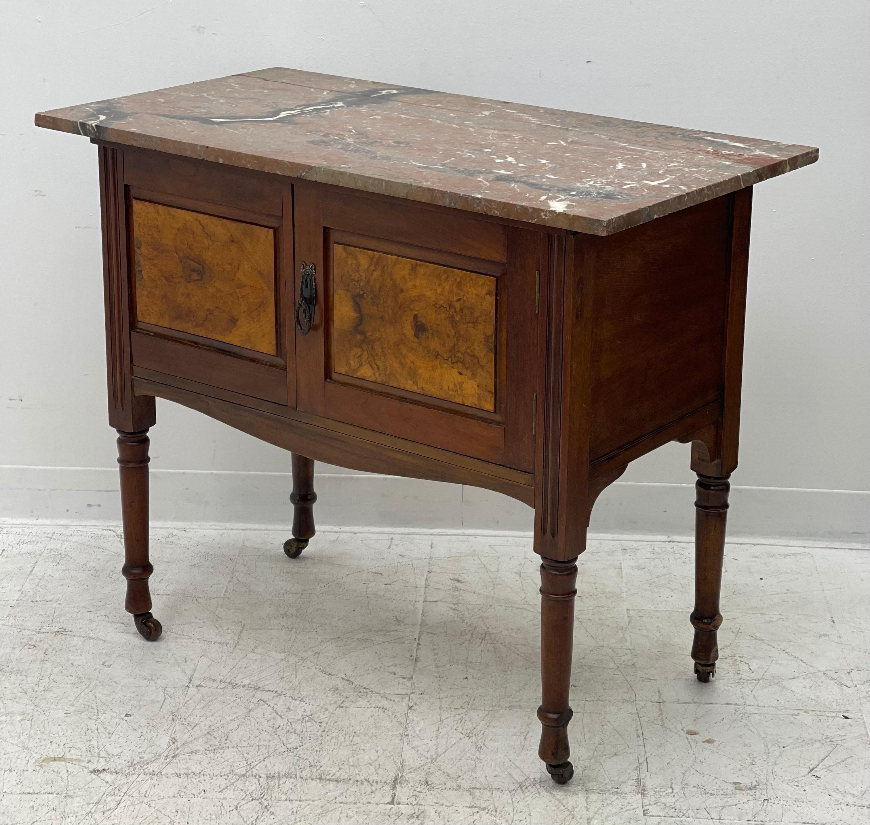 English buffet with marble top and 2 doors. The handles and escutcheons are bronze. It rests on four tapered legs that ends in casters.

Dimensions. Approx 36 W ; 30 H ; 19 D.