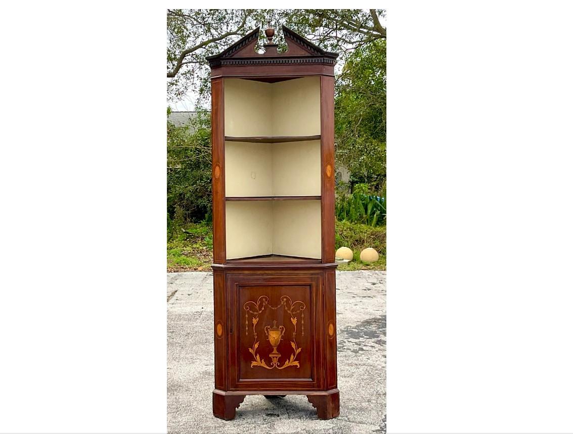 A fabulous vintage Georgian corner cabinet. A chic pediment top with incredible inlay detail on the bottom and sides. Lots of great storage below. Acquired from a Palm Beach estate. 