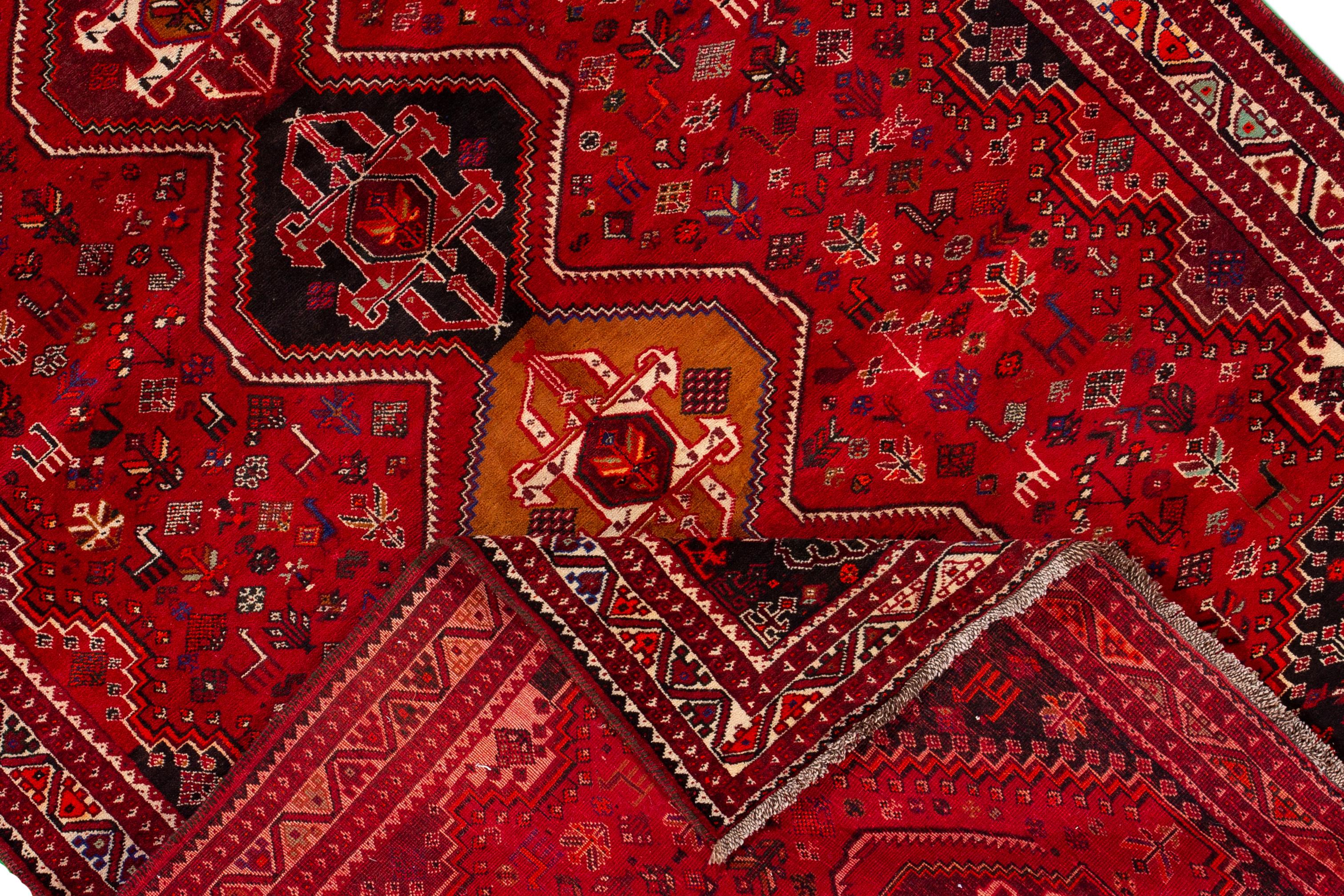 Beautiful vintage Shiraz rug, hand knotted wool with a red field, black and ivory accents, in a center multi medallion design.
This rug measures 7' 5