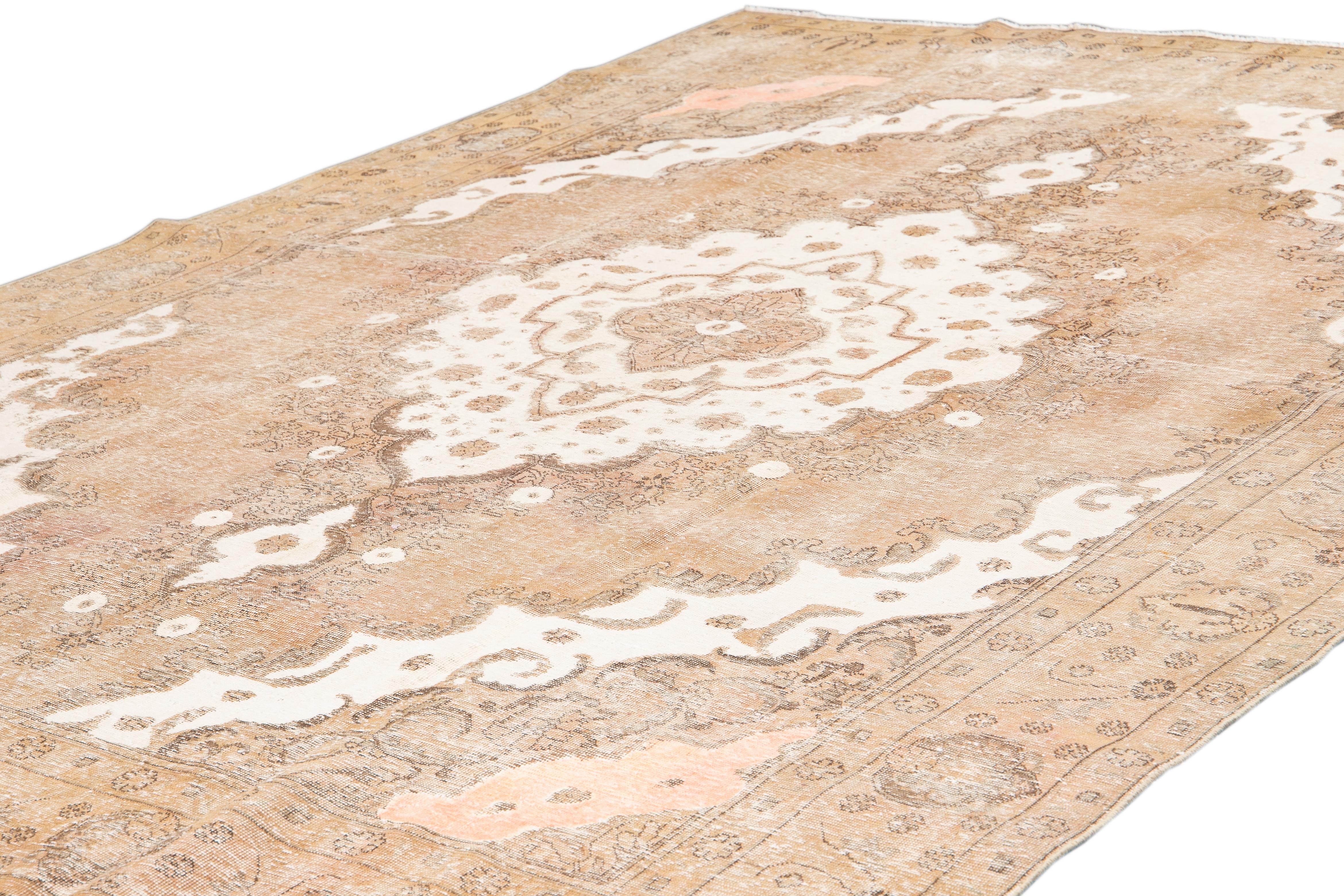 Beautiful vintage Tabriz wool rug, with a tan field, ivory and peach accents in an all-over center medallion design.
This rug measures 9' 2