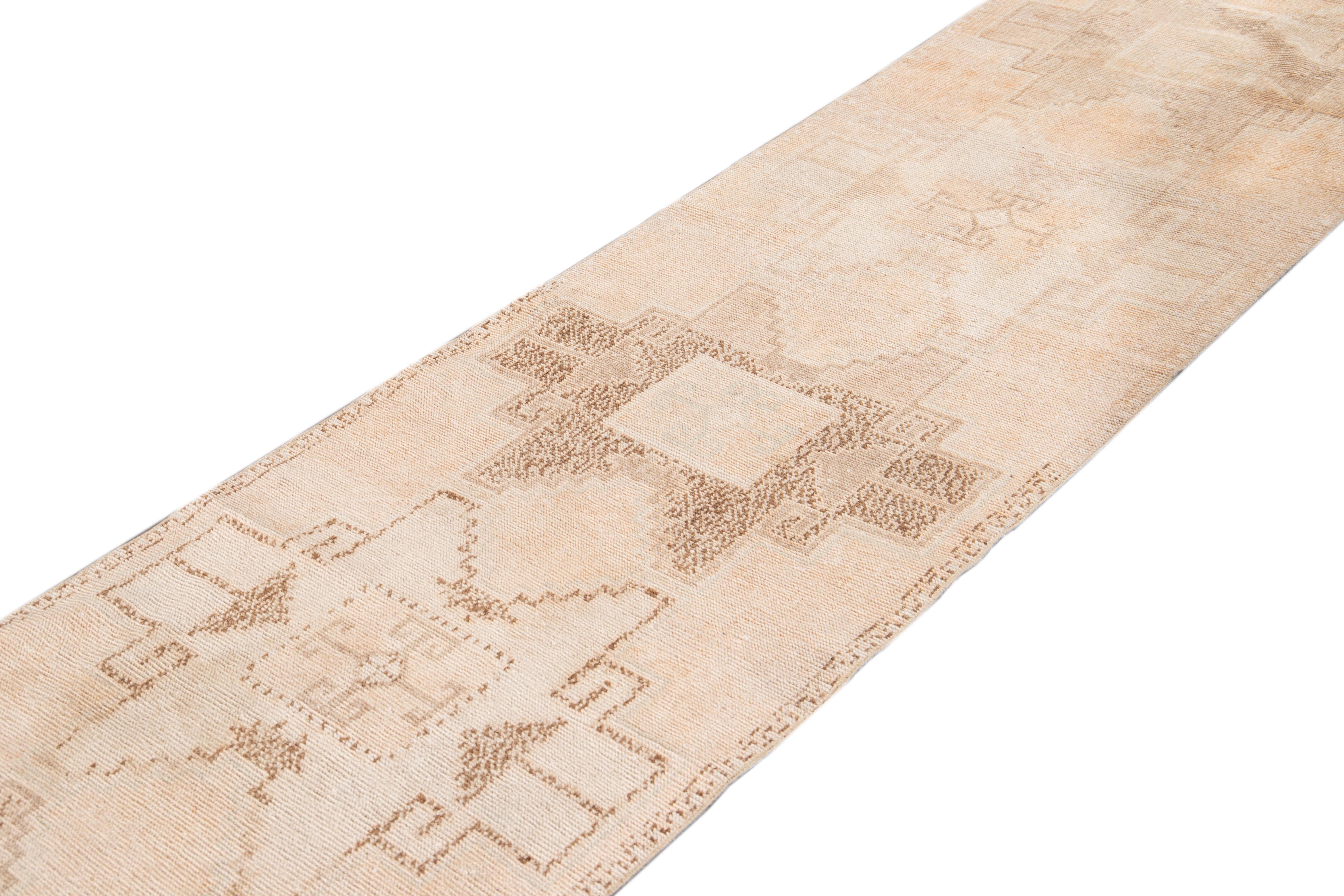 Beautiful antique runner rug, with a light blush field, brown and tan accents in an all-over multi medallion geometric design.

This rug measures 2' 9
