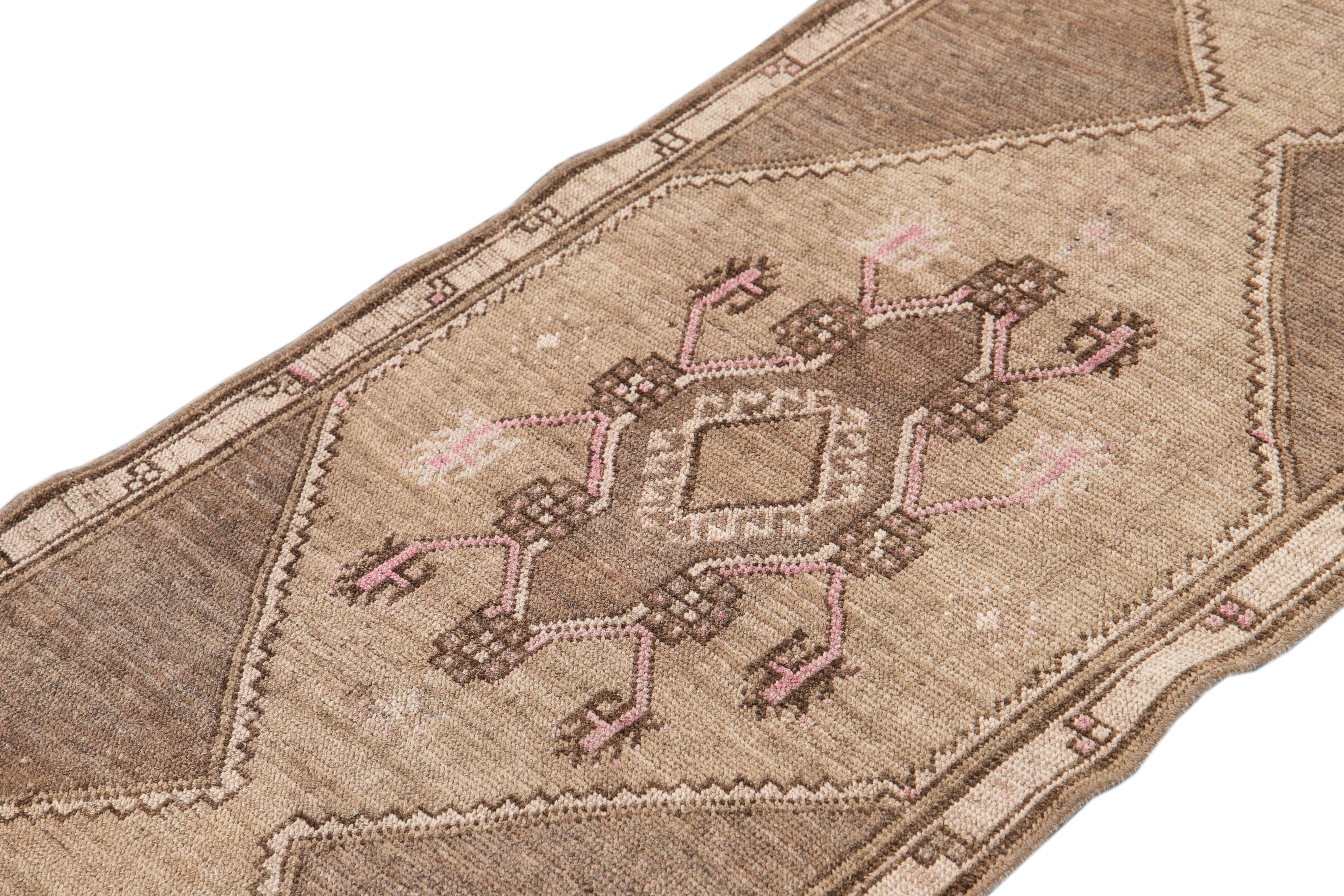 Beautiful antique runner rug, with a dark tan field, brown and pink accents in an all-over multi medallion geometric design.

This rug measures: 2' 8