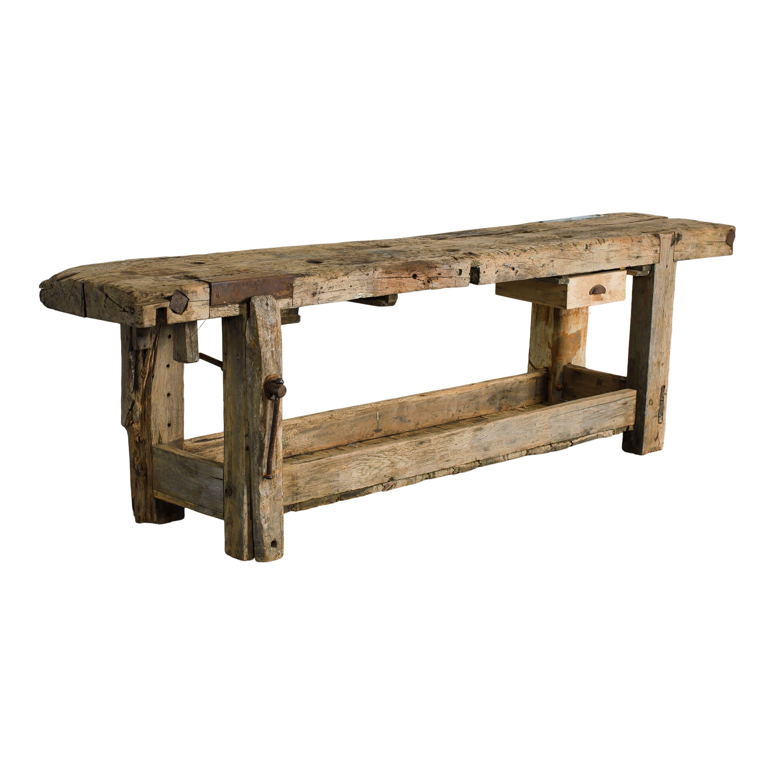 A vintage wood workbench with a drawer and metal details and a lovely patina from years of use. This piece was made and used in France as a workbench. It includes a small drawer with a metal pull on the right side, small metal details throughout
