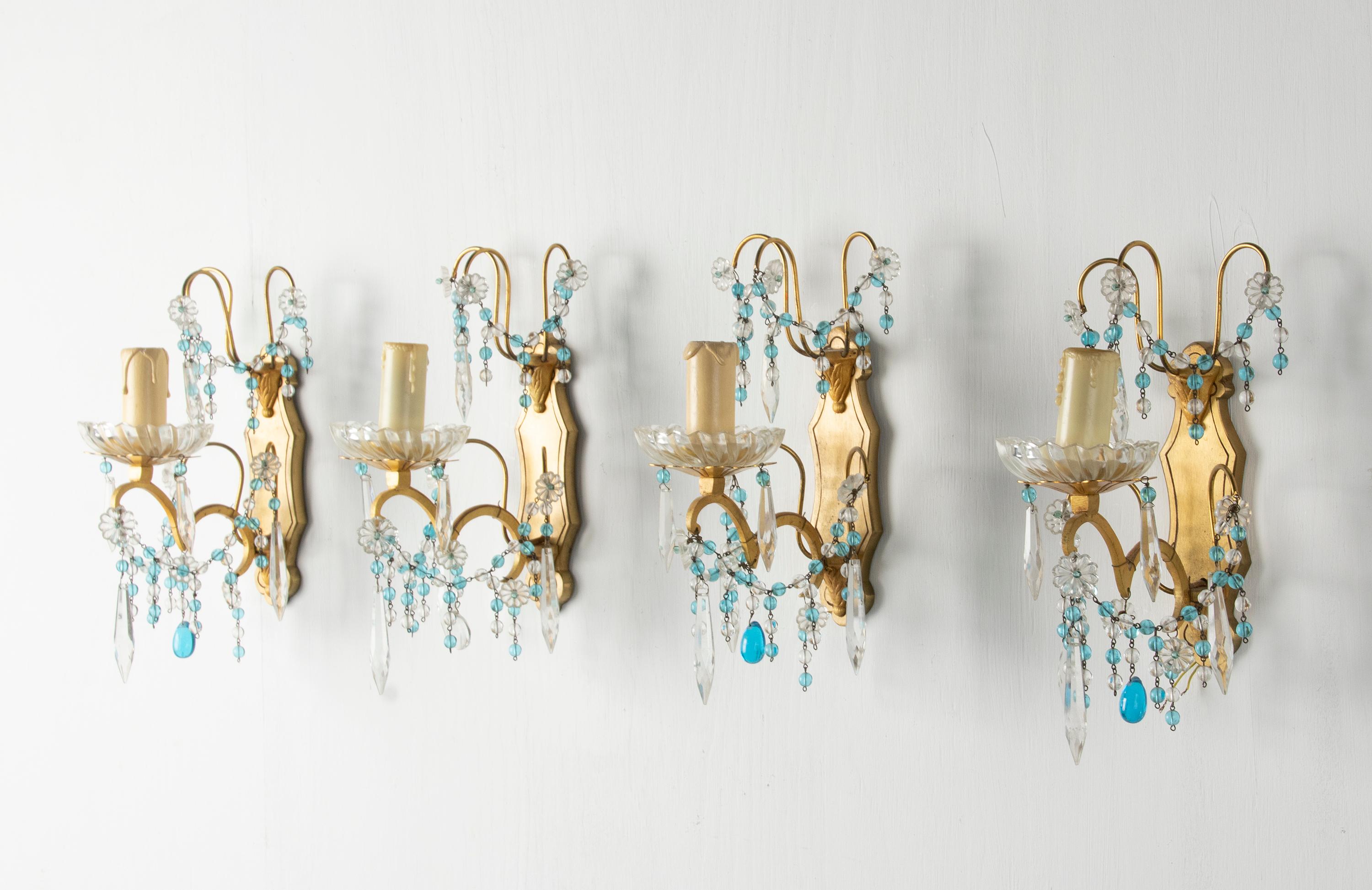 Un conjunto de cuatro apliques electrificados. Con gotas de cristal estilo Murano y sartas de cuentas de cristal. El accesorio es de latón. Cada lámpara tiene un casquillo para una bombilla E14. Fabricado en Italia, hacia 1920-1930. Se han