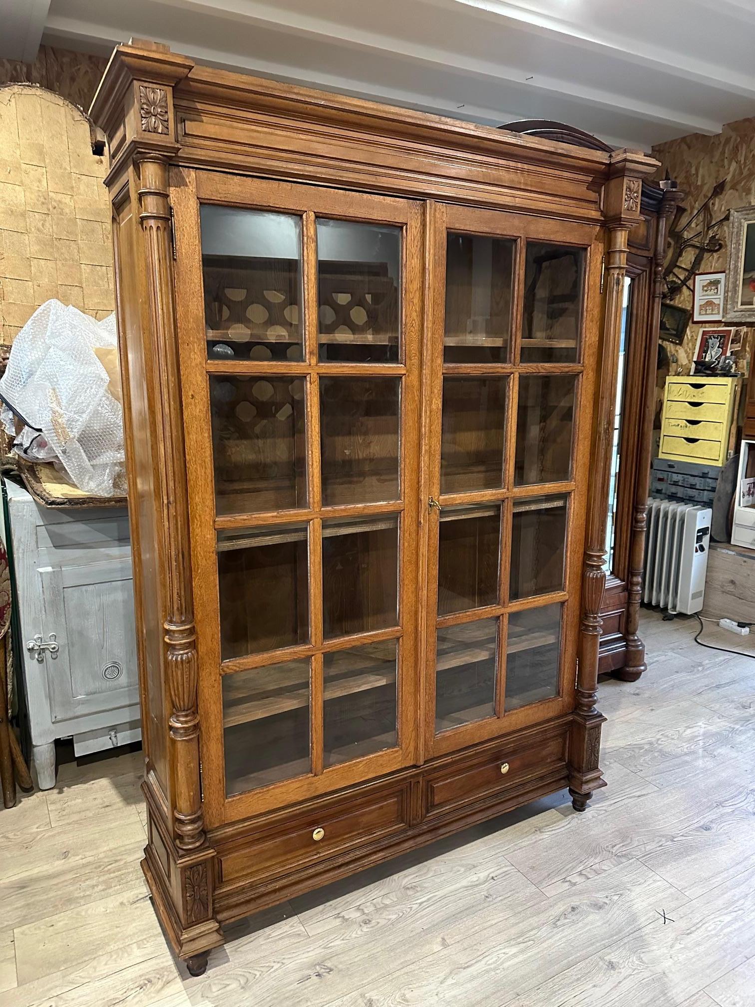 Very beautiful walnut vitrine dating from the beginning of the 20th century. Several removable shelves as you wish. 
Hook on the middle shelf used to hold the door closed.
Two glass doors with wooden squares. Columns on each side which adorn the