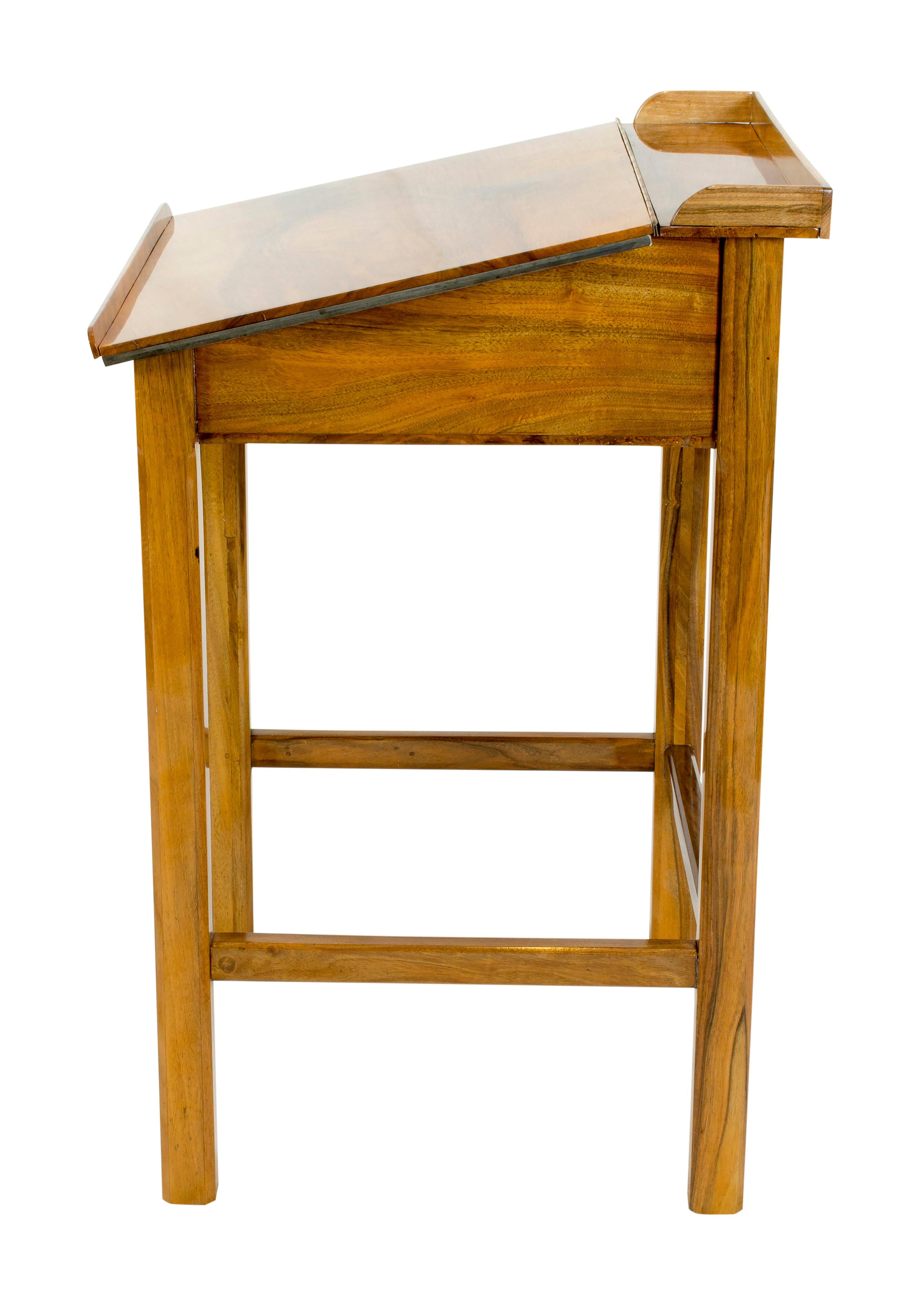 The writing desk is made of solid walnut wood. The desk is from circa 1925 and can be opened with a storage compartment. The foldable writing board is weighted on the underside with iron weights on the edge, so that the base for writing is extremely