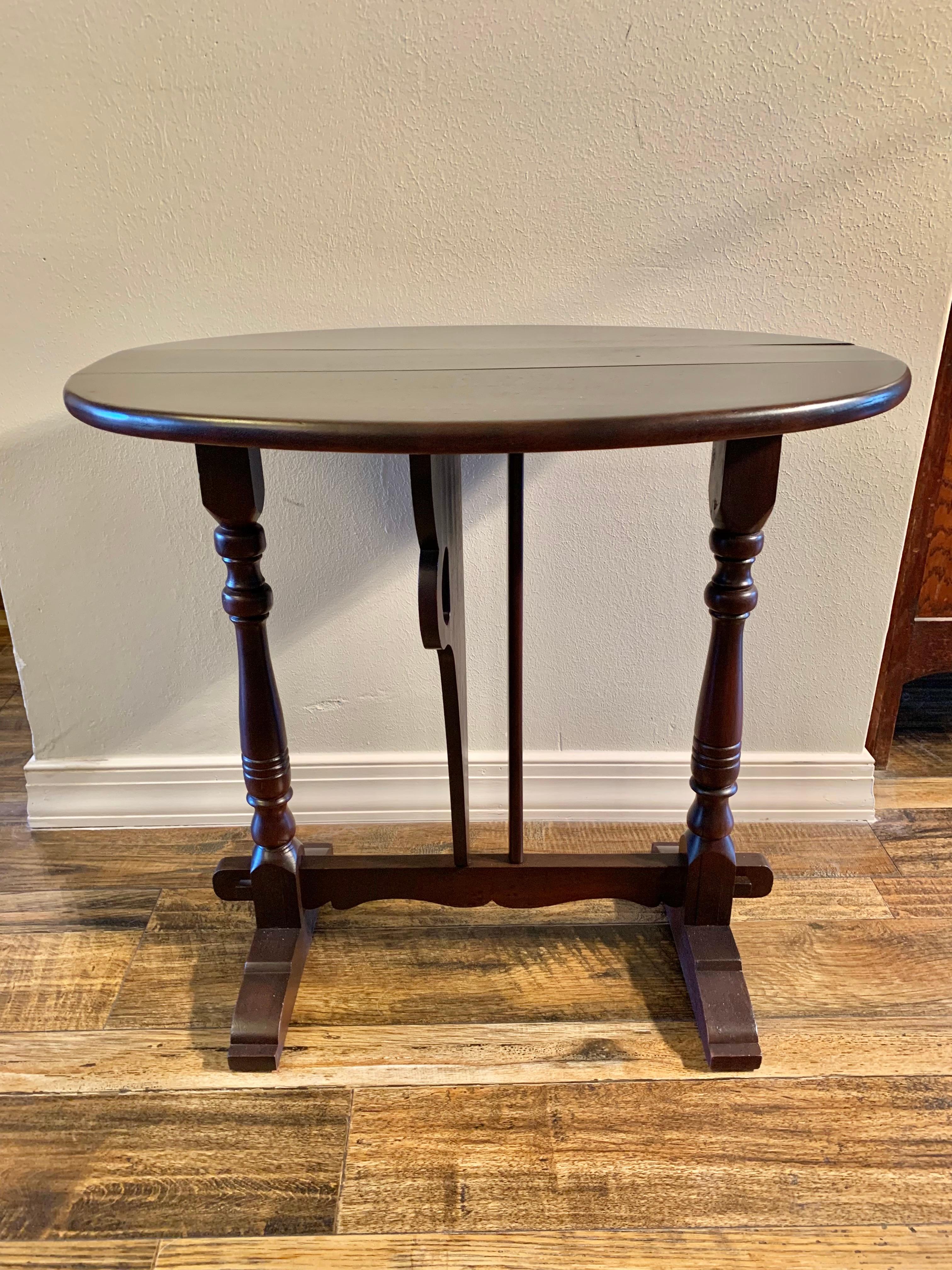 This Drop Leaf Trestle Side Table was crafted from Walnut in the early 1900's. The piece features an oval top supported by two large wing brackets in the shape of butterfly wings, which gives it it's name Butterfly Drop Leaf. The wing brackets swing